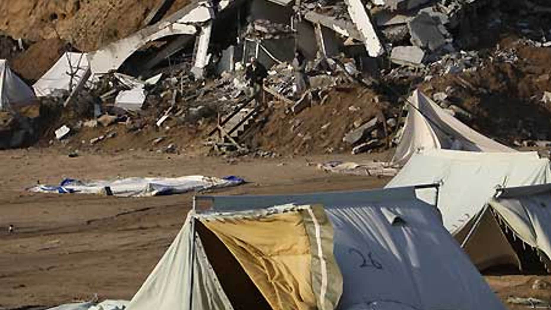 Feb. 21: A Palestinian family, background, walk next to collapsed tents that housed people who had lost their homes in Israel's incursion into Gaza.