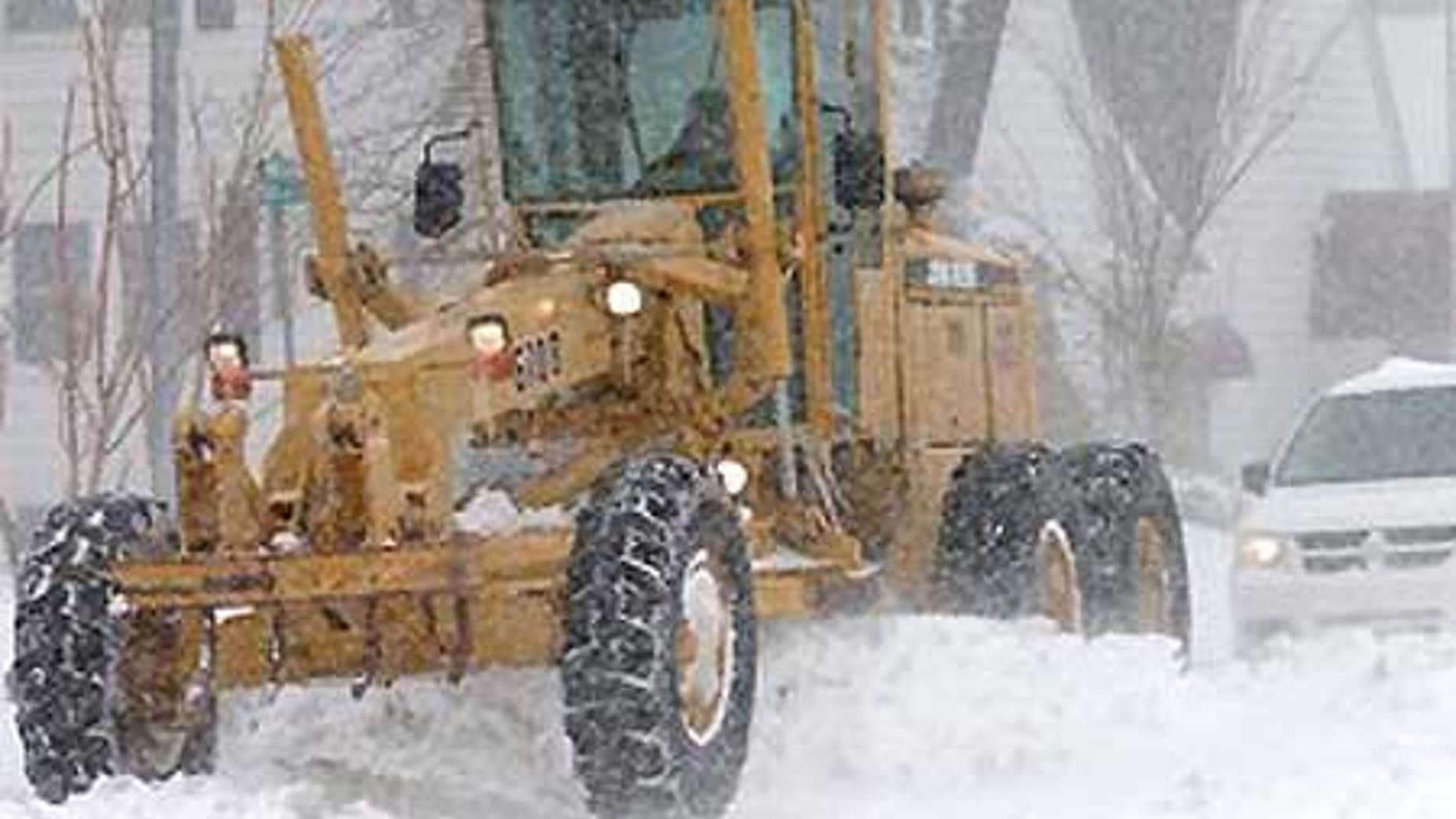 Garden City, Kansas, city employee Jim Brungardt drives a road grader to push fallen snow as snow continues to accumulate.
