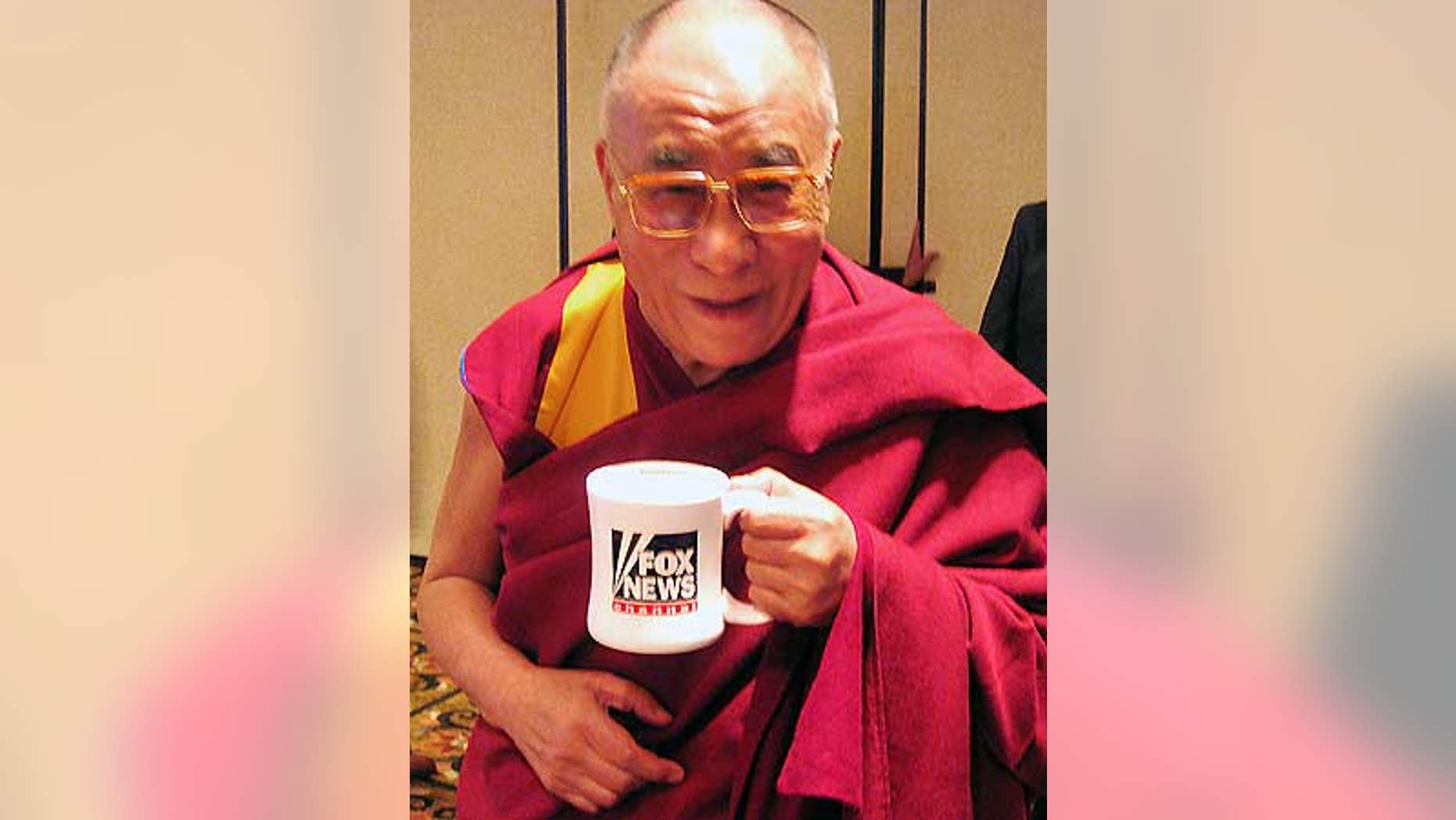 His Holiness the Dalai Lama poses with his FOX News mug after an interview.