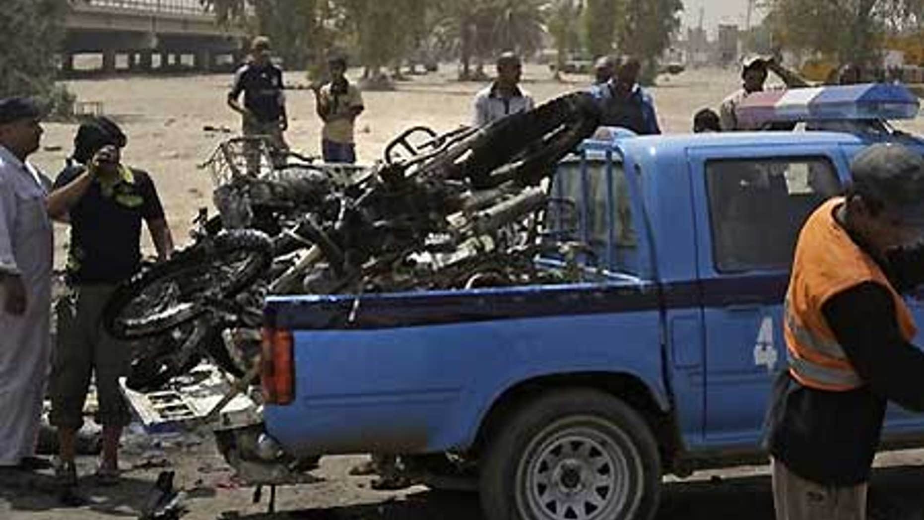 June 26: Iraqis load destroyed motorcycles in Baghdad, Iraq, after a booby-trapped motorcycle exploded in a crowded bazaar in Baghdad.