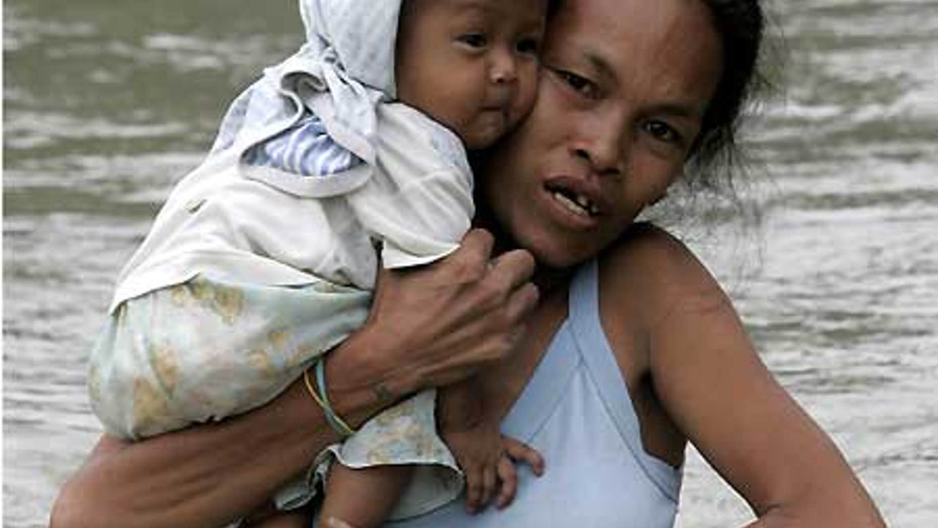 Oct. 2: A mother cuddles her child while wading through floodwaters in Taytay township, Rizal province east of Manila.