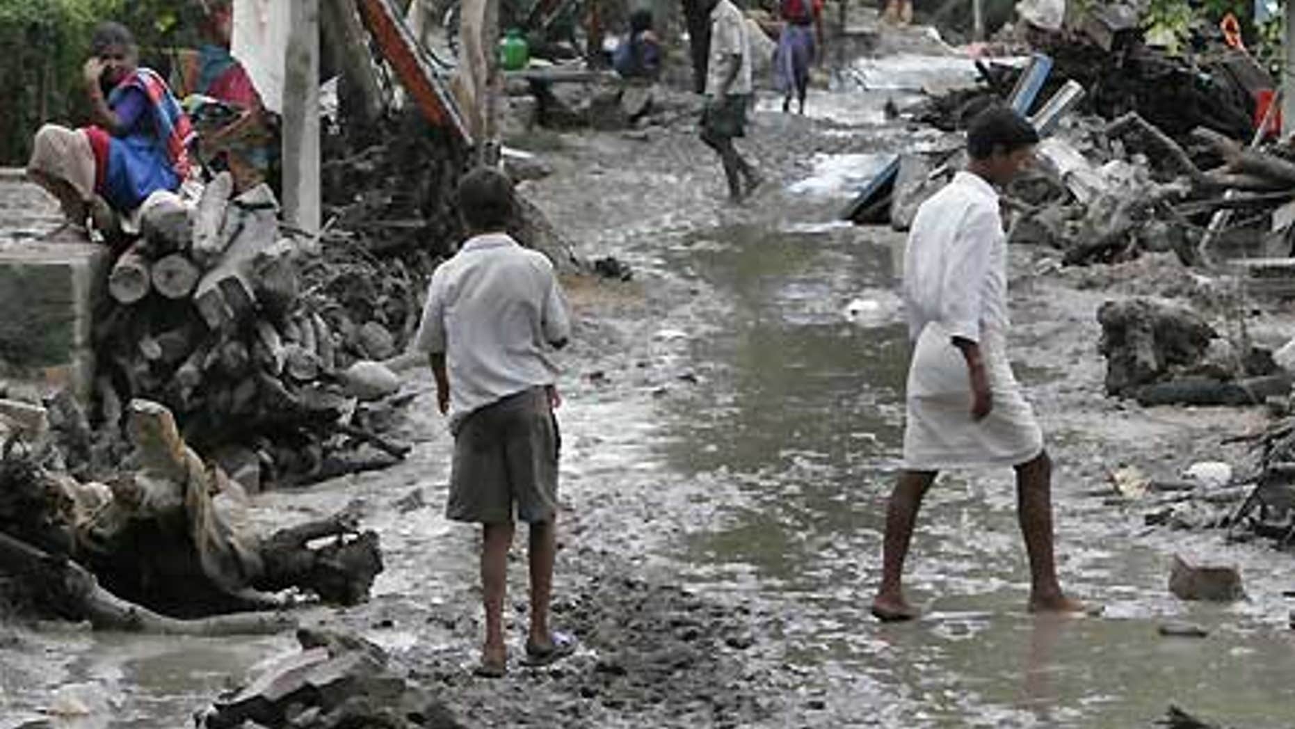 Oct. 3: Villagers walk through a neighborhood badly damaged by floodwaters in Kudadarahal village.
