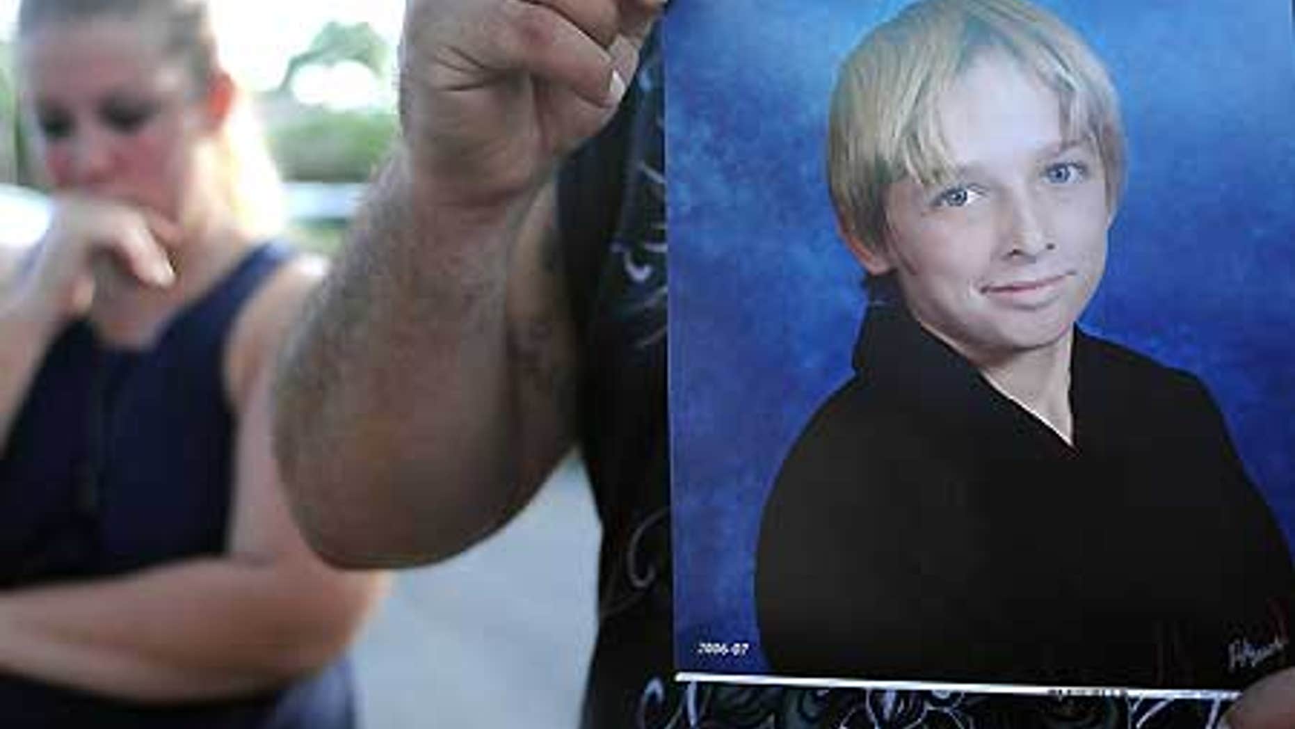 Oct. 13: Danny Martinez, unseen, holds a photo of his brother-in-law, Michael Brewer, 15, who was set on fire.
