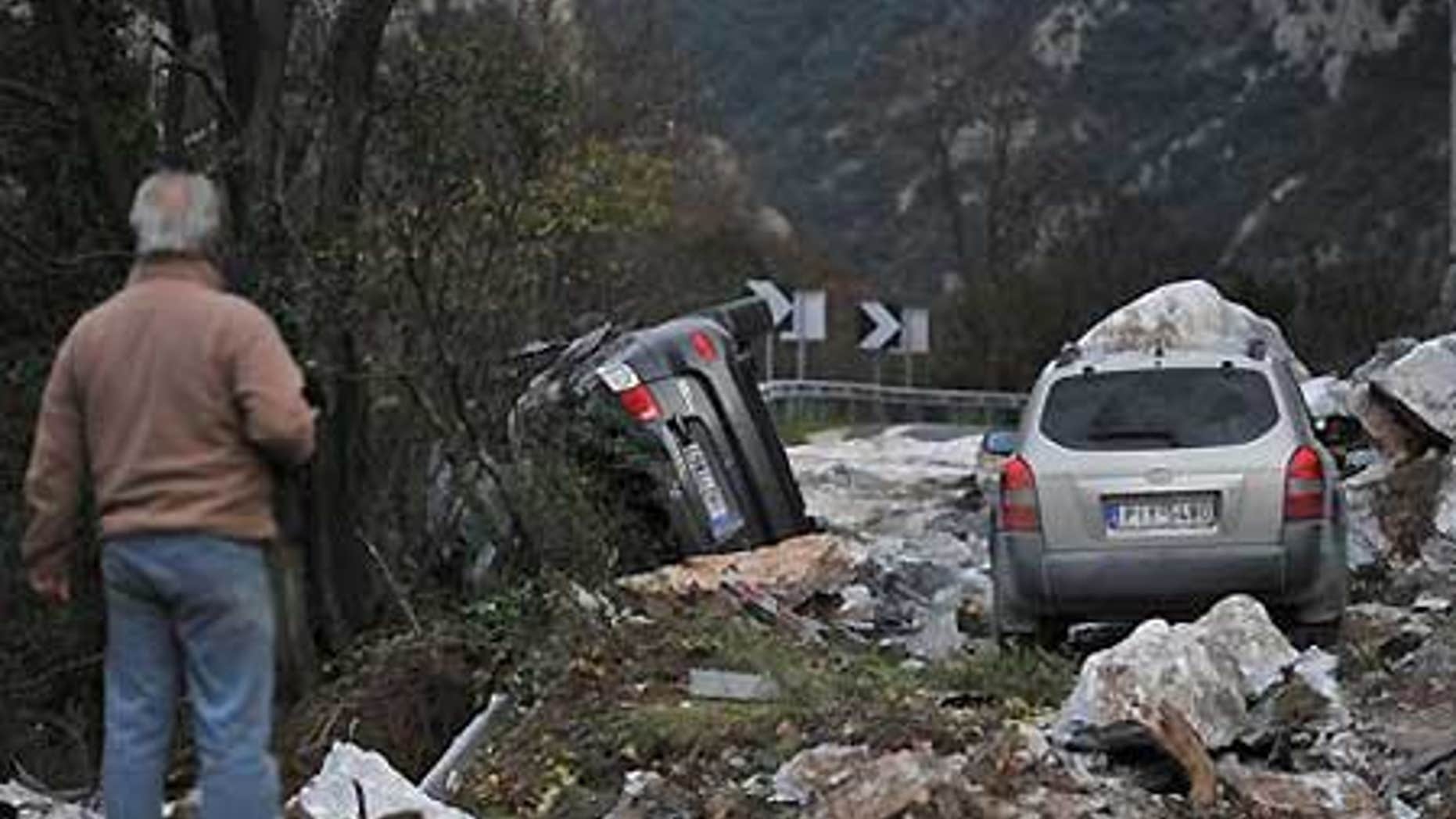 Dec. 17: A man looks at damaged cars next to huge fallen rocks on the main highway south of Thessaloniki, Greece.