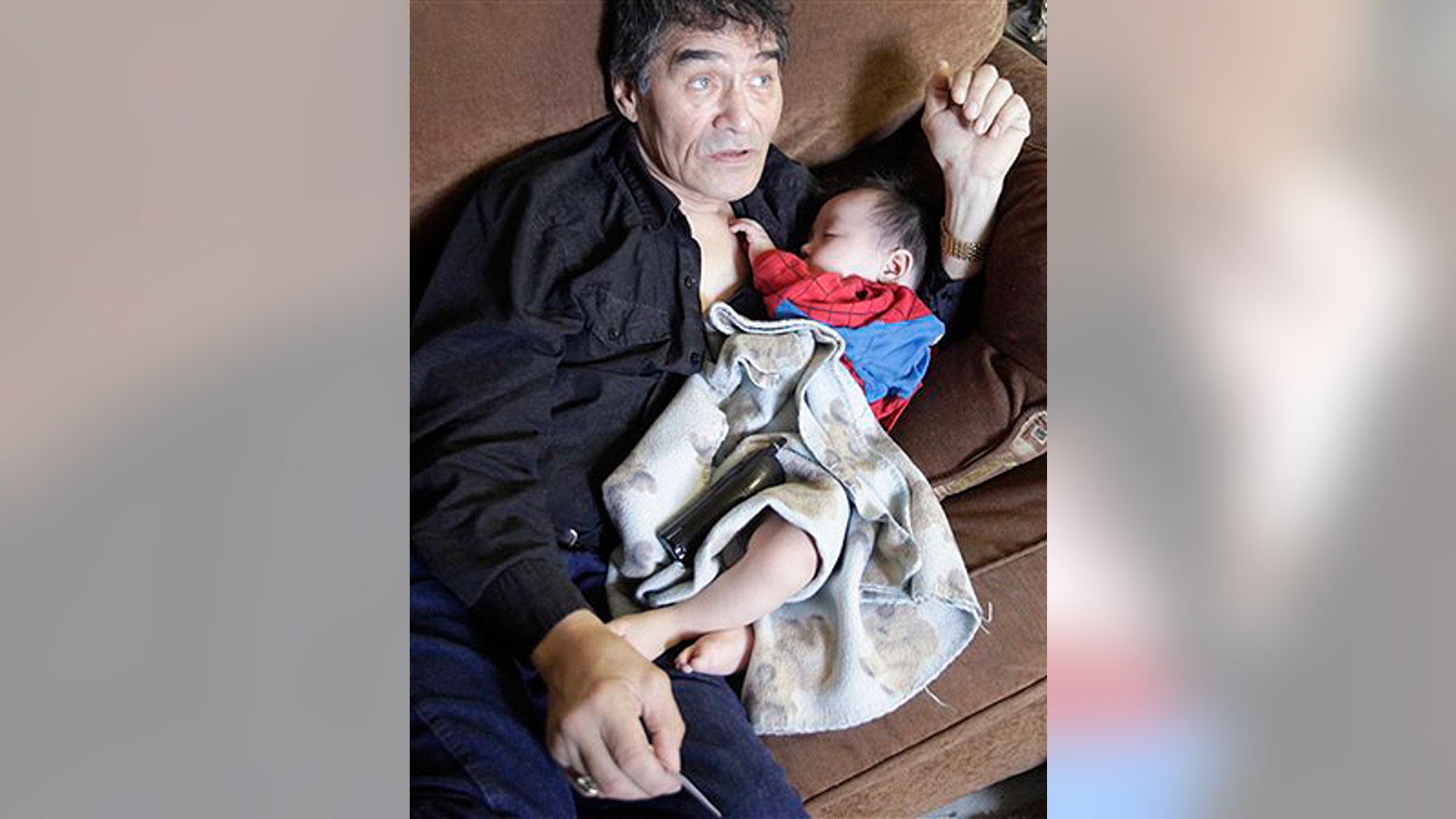 In this Aug. 8, 2009 photo, Henry Nasogaluak Jr. sleeps in the arms of his father Henry Nasogaluak in Tuktoyaktuk, in the Northwest Territories, Canada. Henry Jr. slept in his father's arms as the hunter pondered the future of the boy born last Arctic winter, in the depths of a polar bear season he'd rather forget. "It's too late to be a hunter. I don't want him to do that," Henry Nasogaluak said of his son. "It's a hard life, and it got harder with the ban by the United States." (AP Photo/Rick Bowmer)