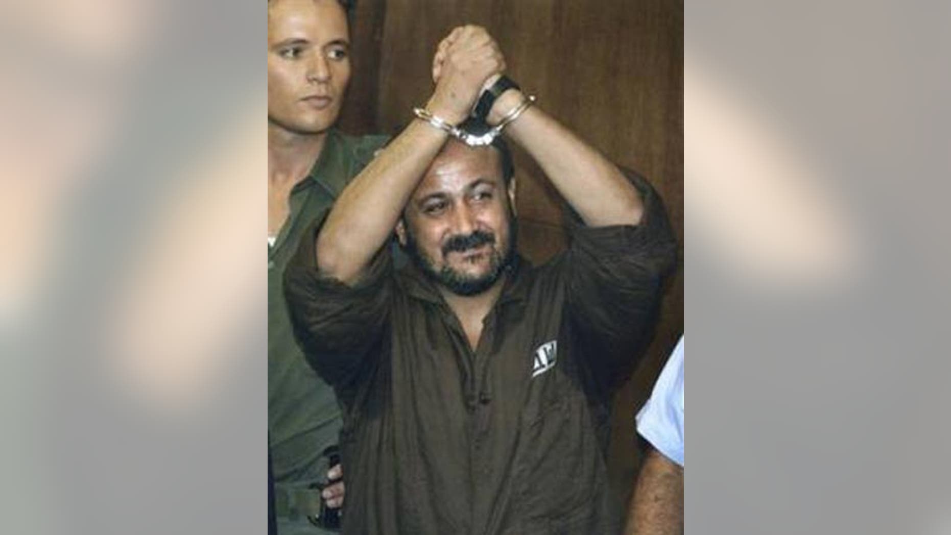 In this Aug. 14, 2002 file photo Marwan Barghouti raises his handcuffed hands in the air on the opening day of his trial at Tel Aviv's District Court