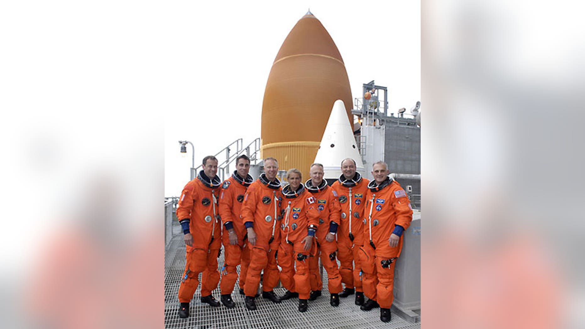 The STS-127 pose next to the top of Endeavour's orange fuel tank and twin solid-fuel rocket boosters.