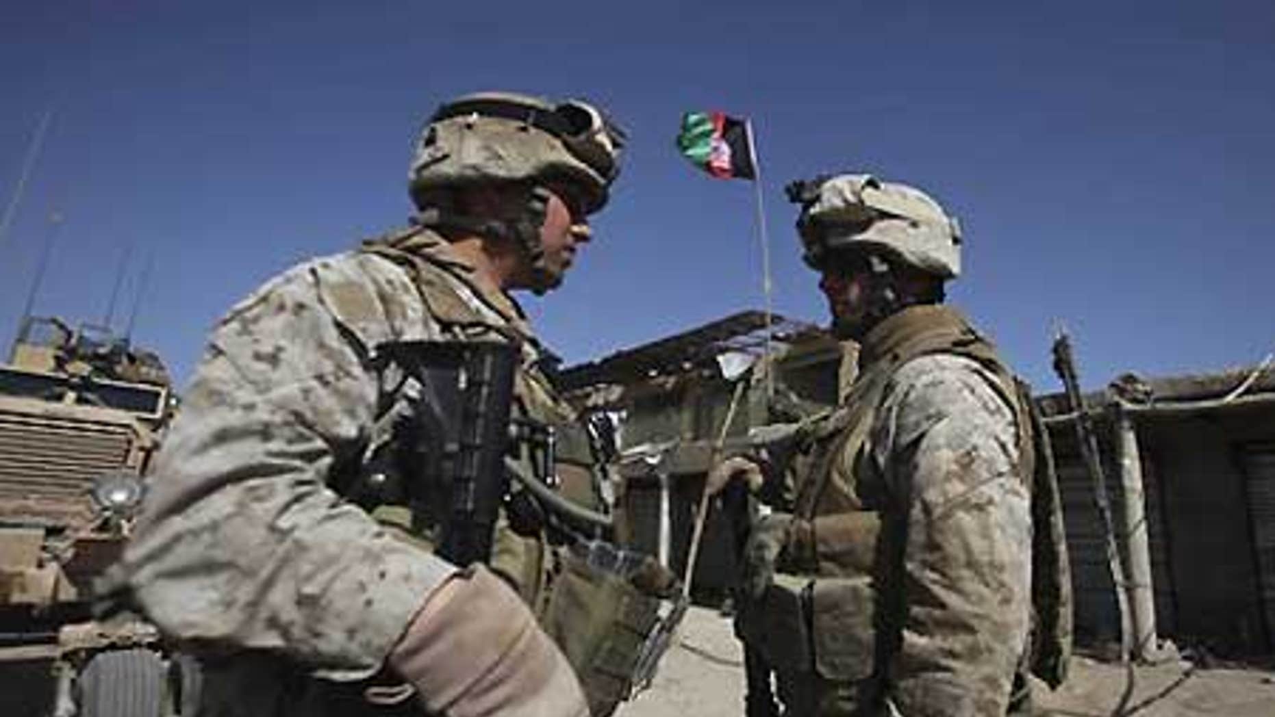 Feb. 17: U.S. Marines with NATO forces talk as newly raised Afghan flag is seen in the background at a deserted market of Marjah, Afghanistan.
