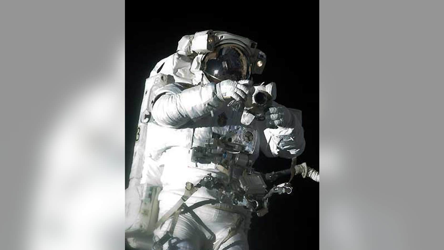 Atlantis shuttle astronaut Robert Satcher Jr. holds a camera during his mission's first spacewalk