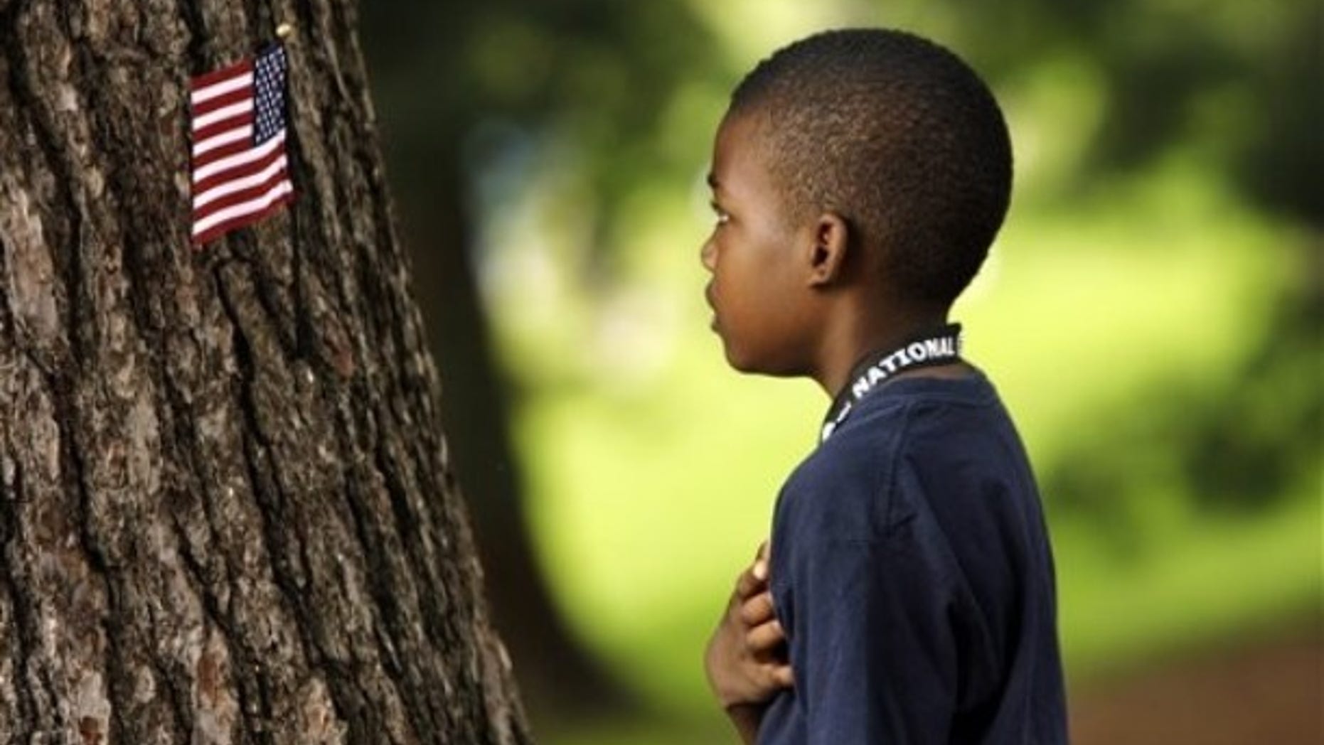 A child says the Pledge of Allegiance after placing an American flag on a tree during the second round of the AT&T National golf tournament at Congressional Country Club, Friday, July 3, 2009, in Bethesda, Md. (AP Photo/Haraz N. Ghanbari)