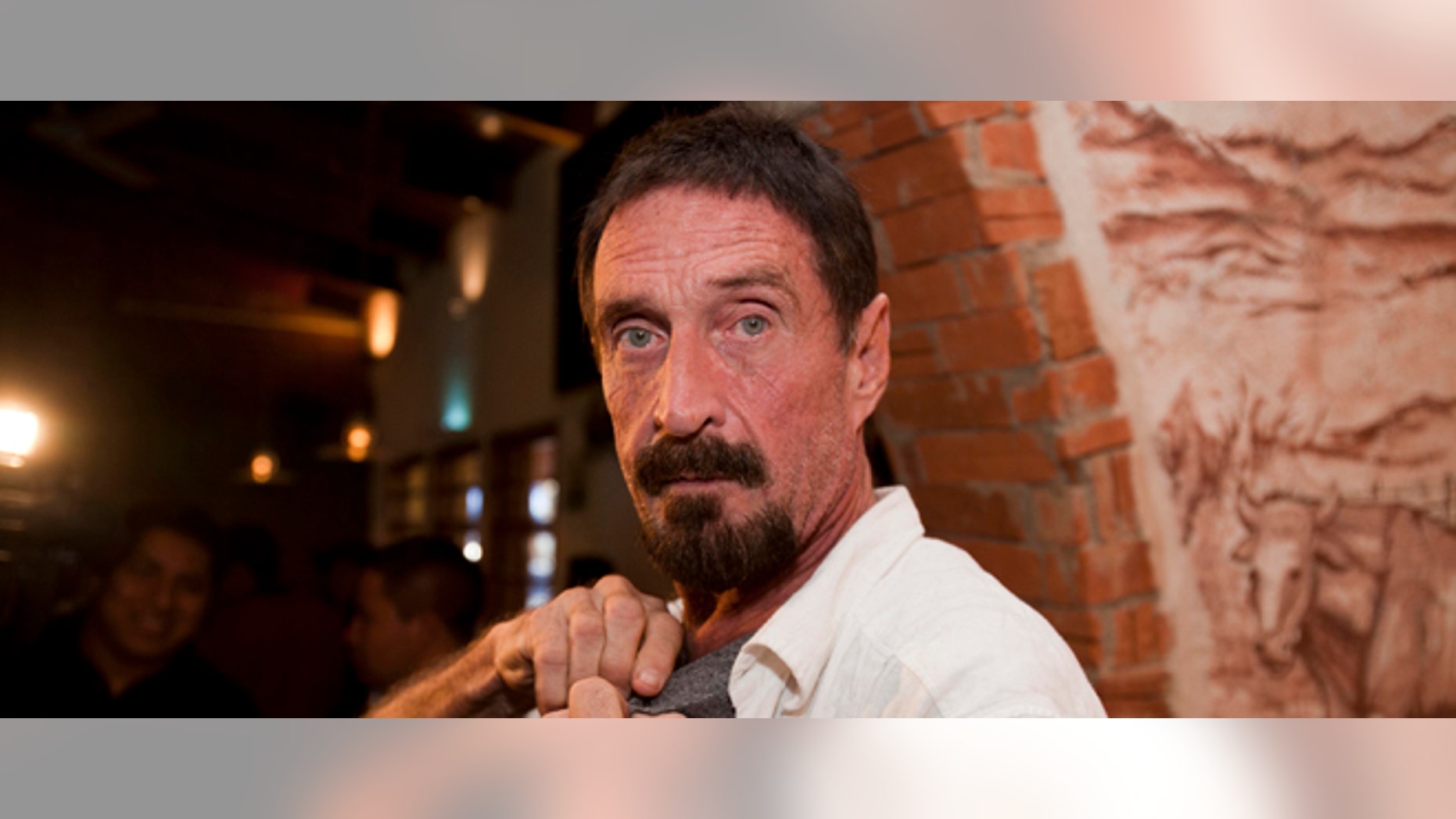 Software company founder John McAfee adjusts a microphone in preparation for an interview in Guatemala City, Tuesday, Dec. 4, 2012. McAfee, 67, has been identified as a "person of interest" in the killing of his neighbor in Belize, 52-year-old Gregory Faull. Police are urging McAfee to come in for questioning. The anti-virus company founder fled Belize and is seeking political asylum in Guatemala, according to his lawyer Telesforo Guerra. (AP Photo/Moises Castillo)