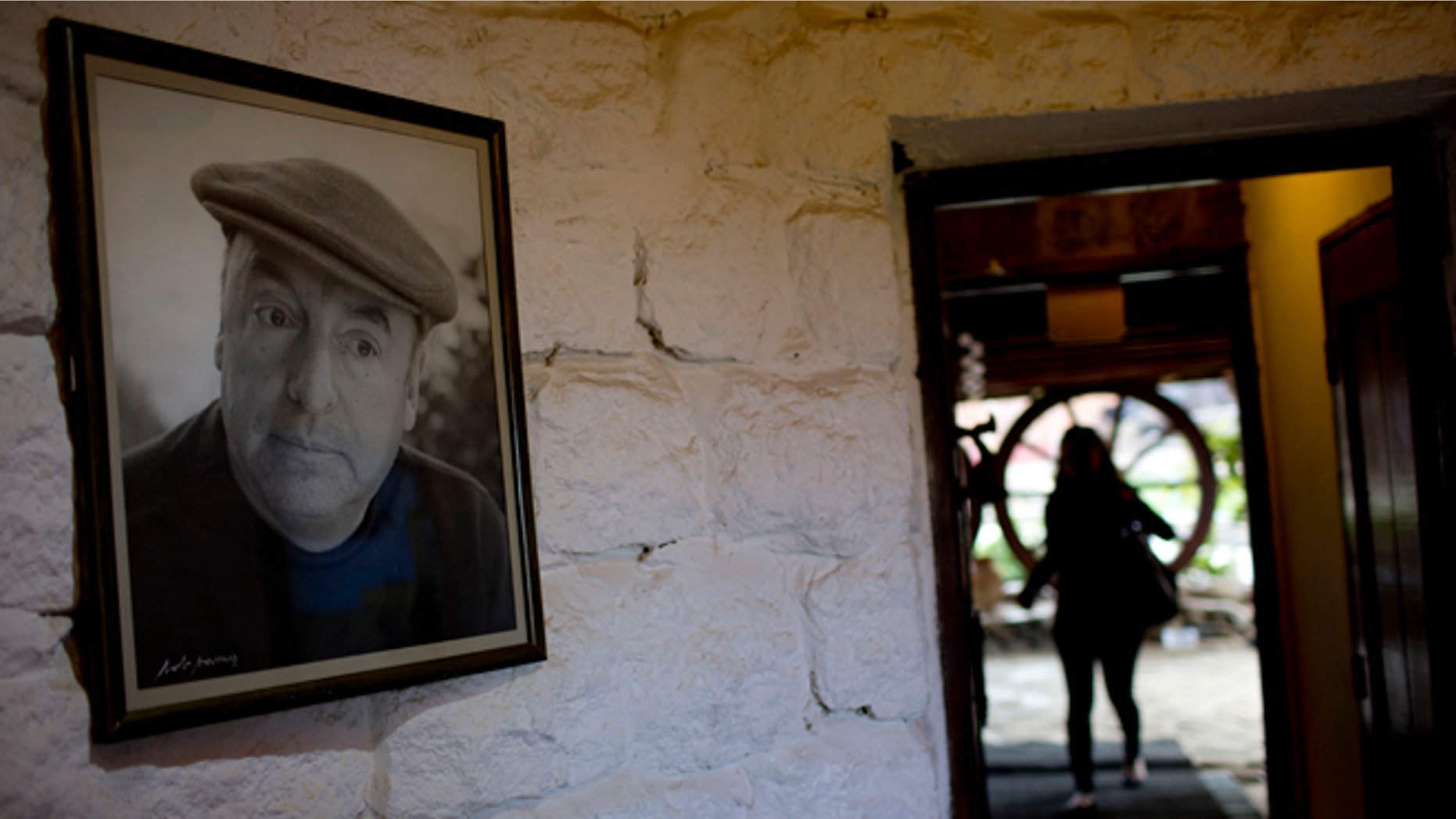 In this April 26, 2015 photo, a framed photo of Nobel Prize-winning poet Pablo Neruda hangs on a wall, as a tourist enters his favorite home in Isla Negra, Chile. (AP Photo/Natacha Pisarenko)