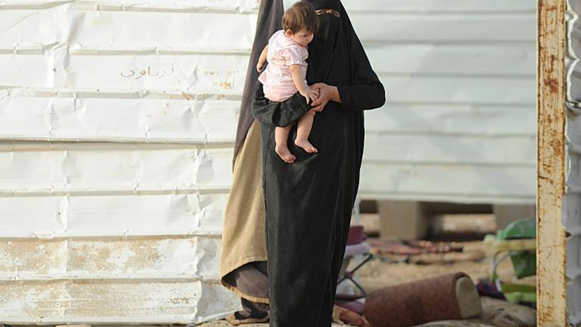 A stateless woman carries her child at her makeshift shelter in an impoverished neighborhood of Riyadh on July 10, 2013