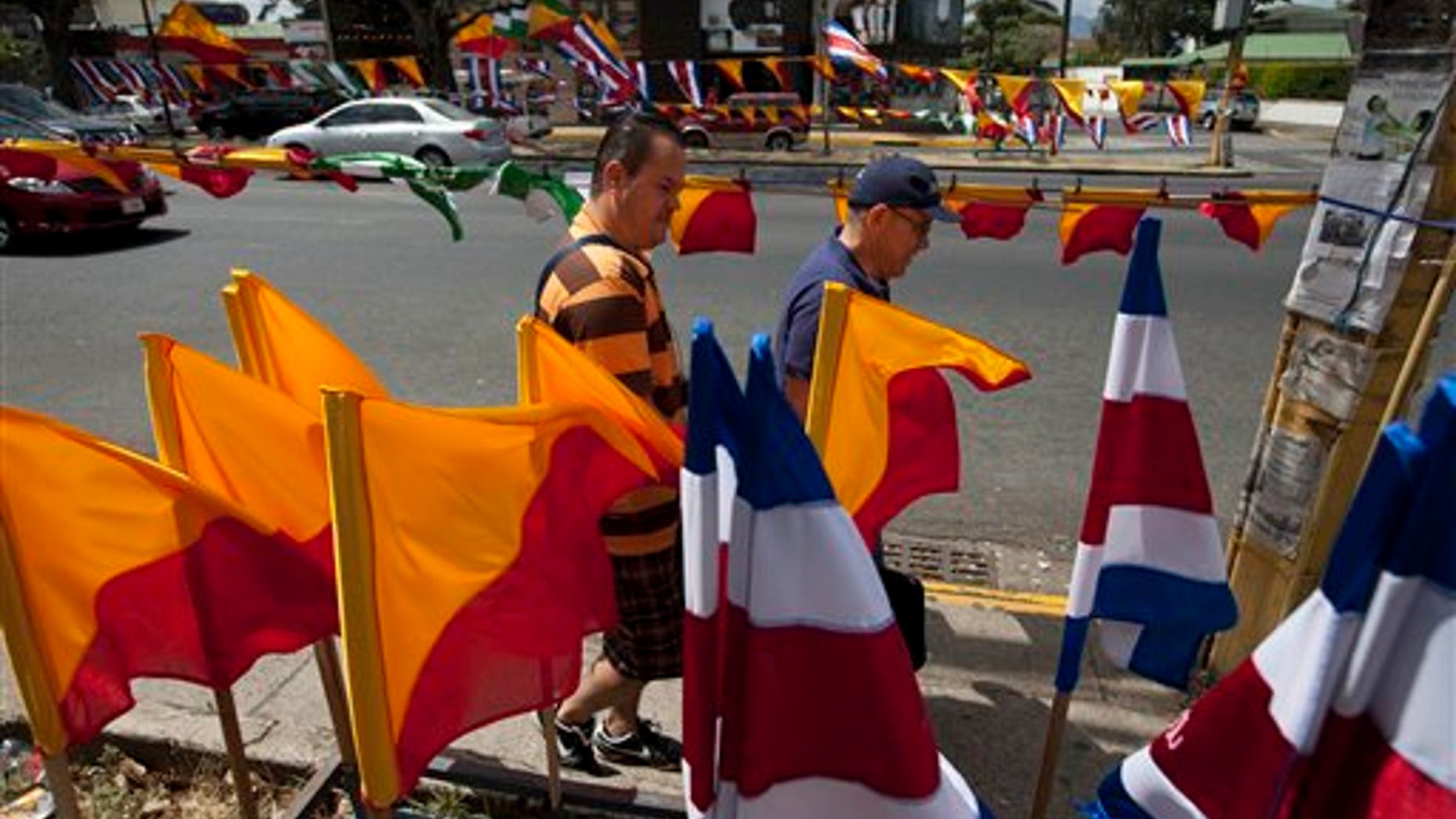 CORRECTS NAME TO LUIS GUILLERMO SOLIS - Men walk next to Costa Rican flags and political party flags, in San Jose, Costa Rica, Saturday, April 5, 2014. Costa Rica will vote on the Sundays runoff presidential election between Luis Guillermo Solis, presidential candidate of Citizen's Action Party and ruling party candidate Johnny Araya. (AP Photo/Moises Castillo)
