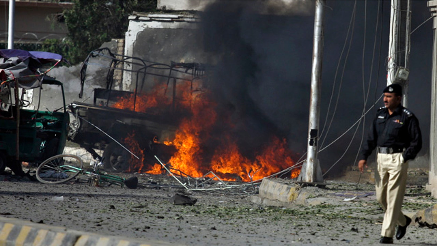 Sept. 7: Pakistani police officer walks past burning vehicle at the site of suicide bombing in Quetta, Pakistan.