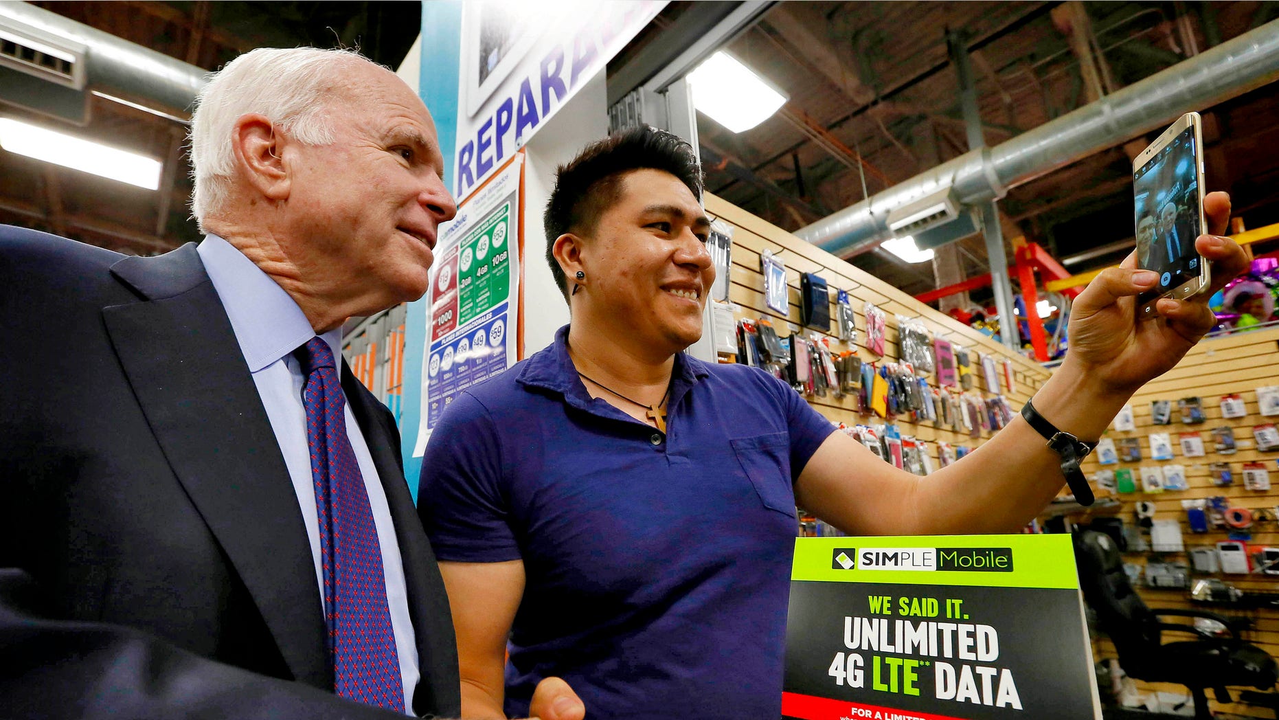 U.S. Sen. John McCain, R-Ariz., poses for a selfie with shop owner Aron Mercado at the El Mercado De Los Cielos mall prior to announcing the launch of the âUnidos Con McCainâ Hispanic coalition, Thursday, Oct. 15, 2015, in Phoenix. McCain is trying to woo Hispanic voters to his re-election effort by putting together a coalition of Latino business leaders who back the Republican. (AP Photo/Matt York)