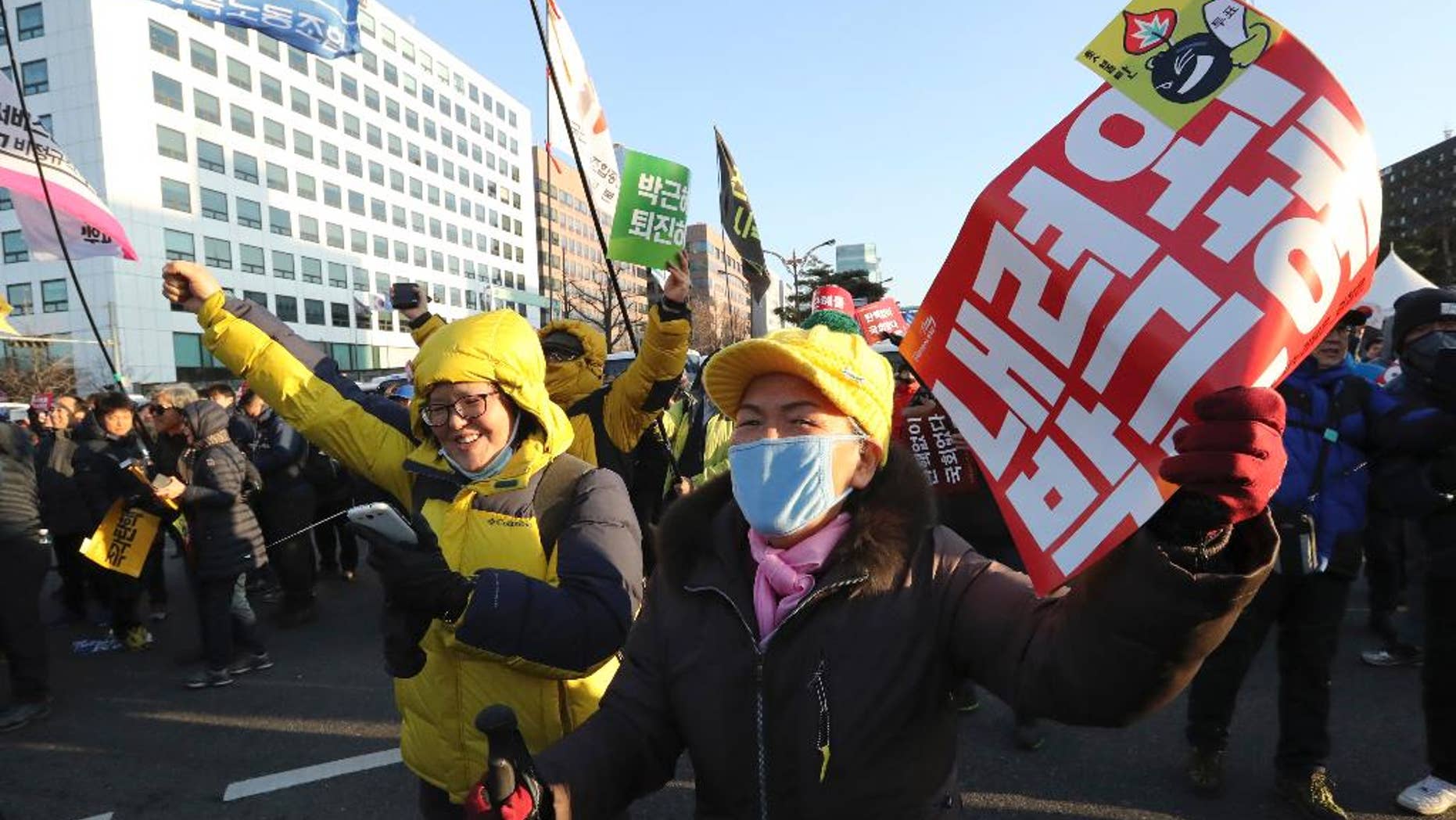 Protesters cheer after hearing the news of President Park Geun-hye's impeachment in front of the National Assembly in Seoul, South Korea, Friday, Dec. 9, 2016. South Korean lawmakers on Friday impeached Park, a stunning and swift fall for the country's first female leader amid protests that drew millions into the streets in united fury. The letters read "Step down, Park Geun-hye." (AP Photo/Lee Jin-man)