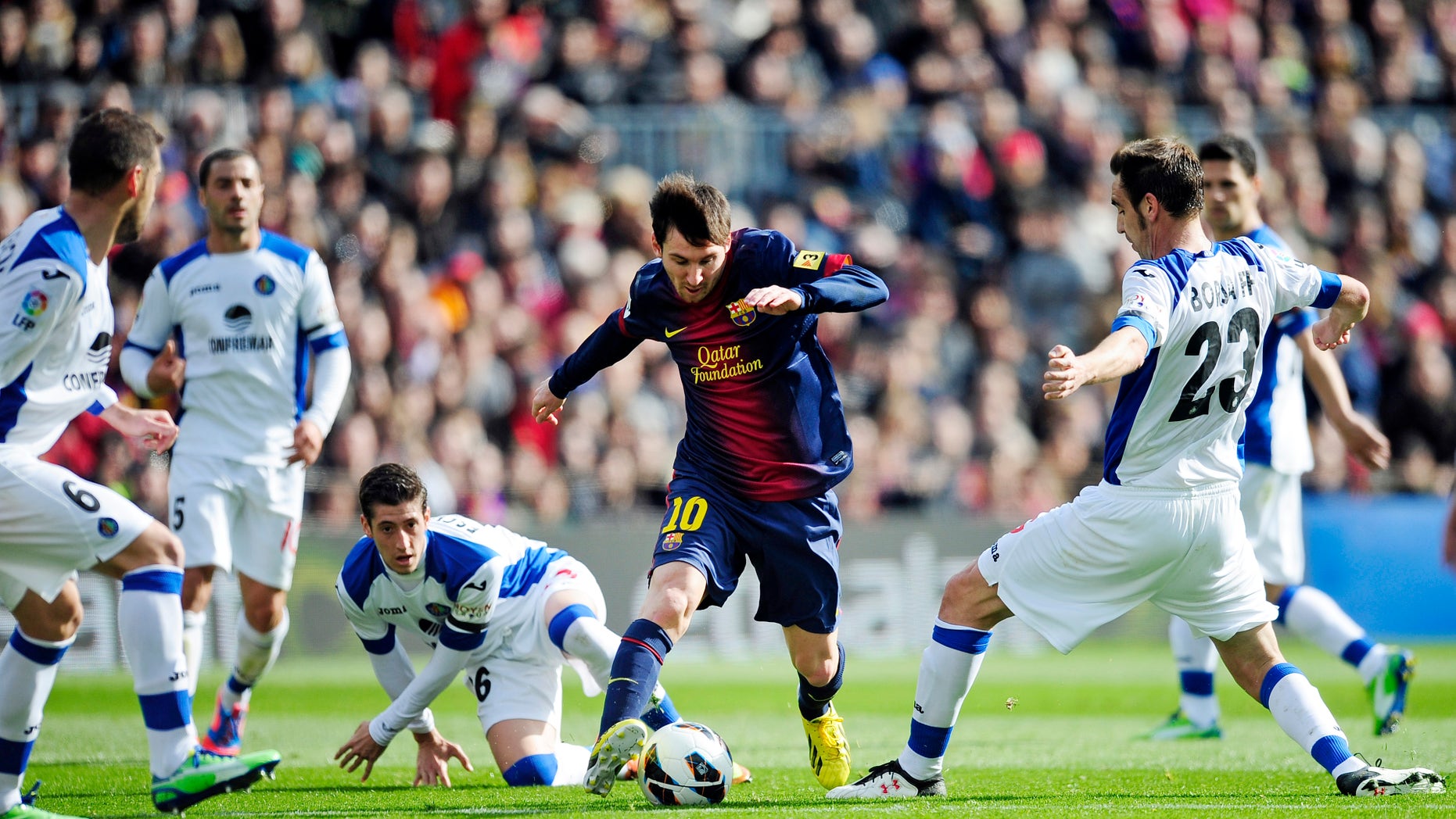 FC Barcelona's Lionel Messi from Argentina, center, duels for the ball against Getafe's Alberto Lopo, center left, and Borja Fernandez, right, during a Spanish La Liga soccer match, at the Camp Nou stadium in Barcelona, Spain, Sunday, Feb. 10, 2013. (AP Photo/Manu Fernandez)