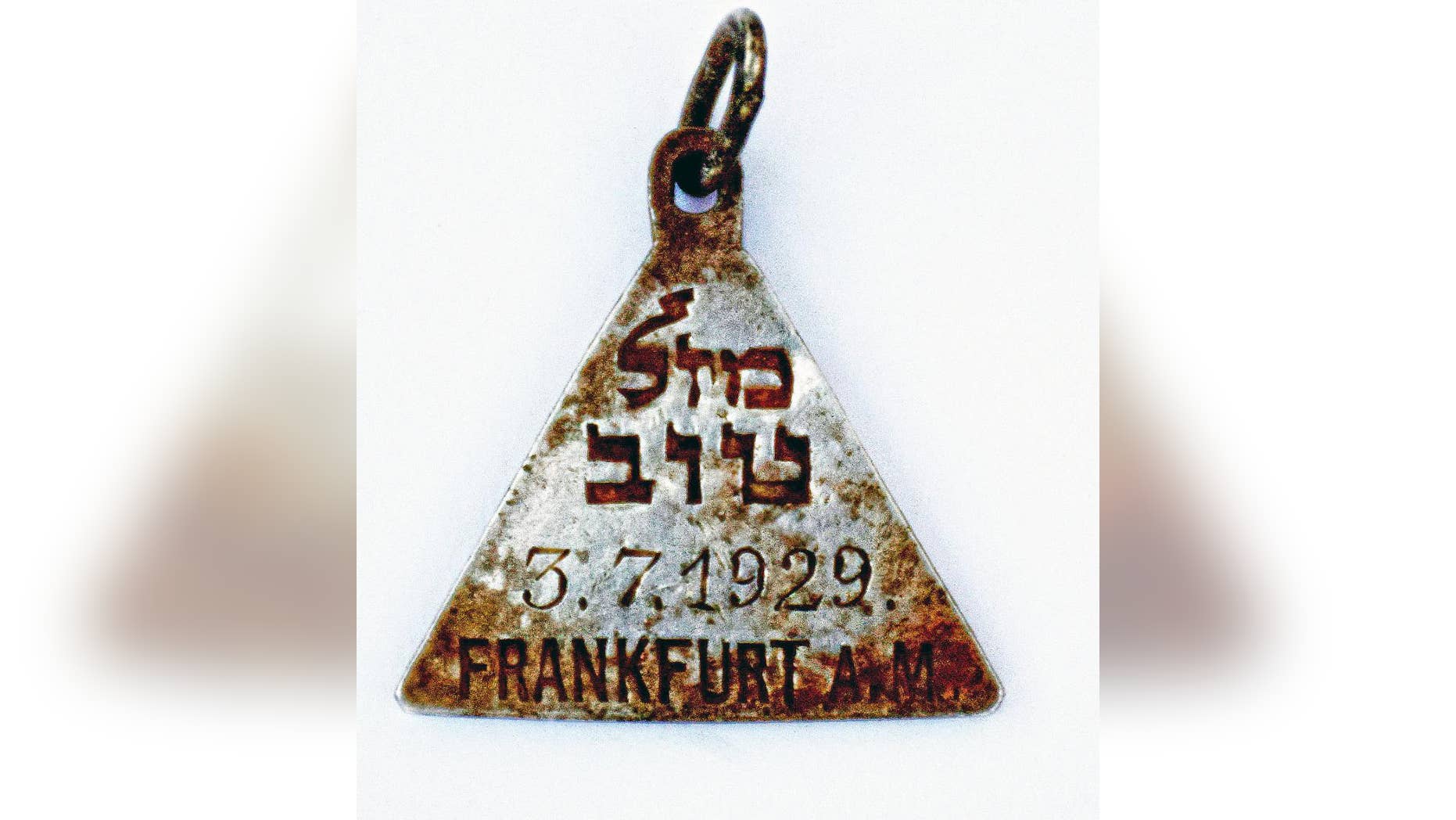 This undated photograph released by the Israel Antiquities Authority shows a pendant that appears identical to one belonging to Anne Frank, Israel's Yad Vashem Holocaust memorial said Sunday. Yad Vashem says it has ascertained the pendant belonged to Karoline Cohn _ a Jewish girl who perished at Sobibor and may have been connected to the famous diarist. Both were born in Frankfurt in 1929 and historians have found no other pendants like theirs. The triangular piece found has the words "Mazal Tov" written in Hebrew on one side along with Cohn's date of birth and the Hebrew letter "heh," an initial for God, as well as three Stars of David on the other. (Yoram Haimi, Israel Antiquities Authority via AP)