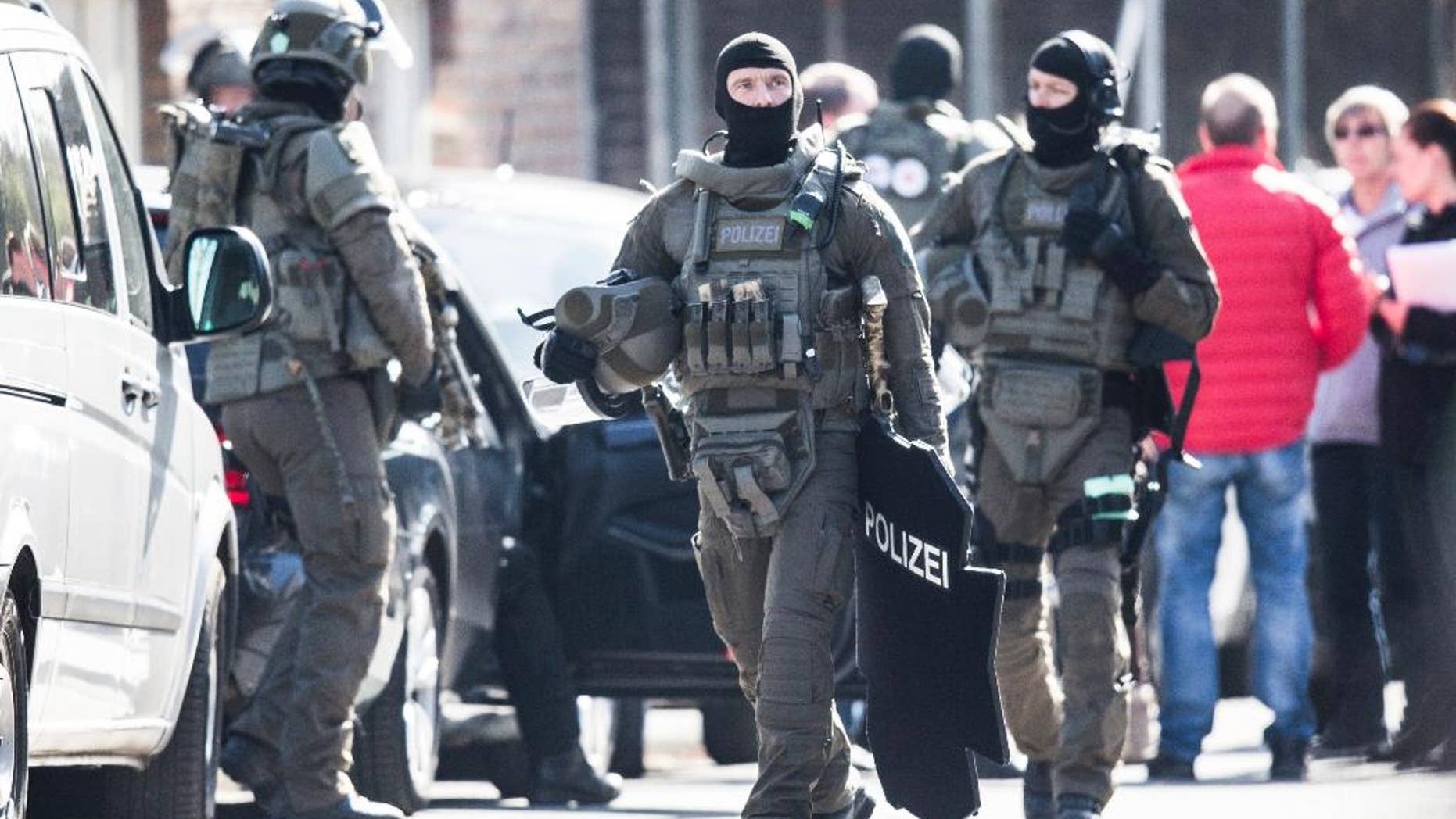 Officers of the special forces walk on a street in Duisburg, Germany, Thursday, March 16, 2017. An armed man robbed a bank on Thursday morning in Duisburg. According to first insights of the police, the man is still inside the building together with two employees. (Marcel Kusch/dpa via AP)