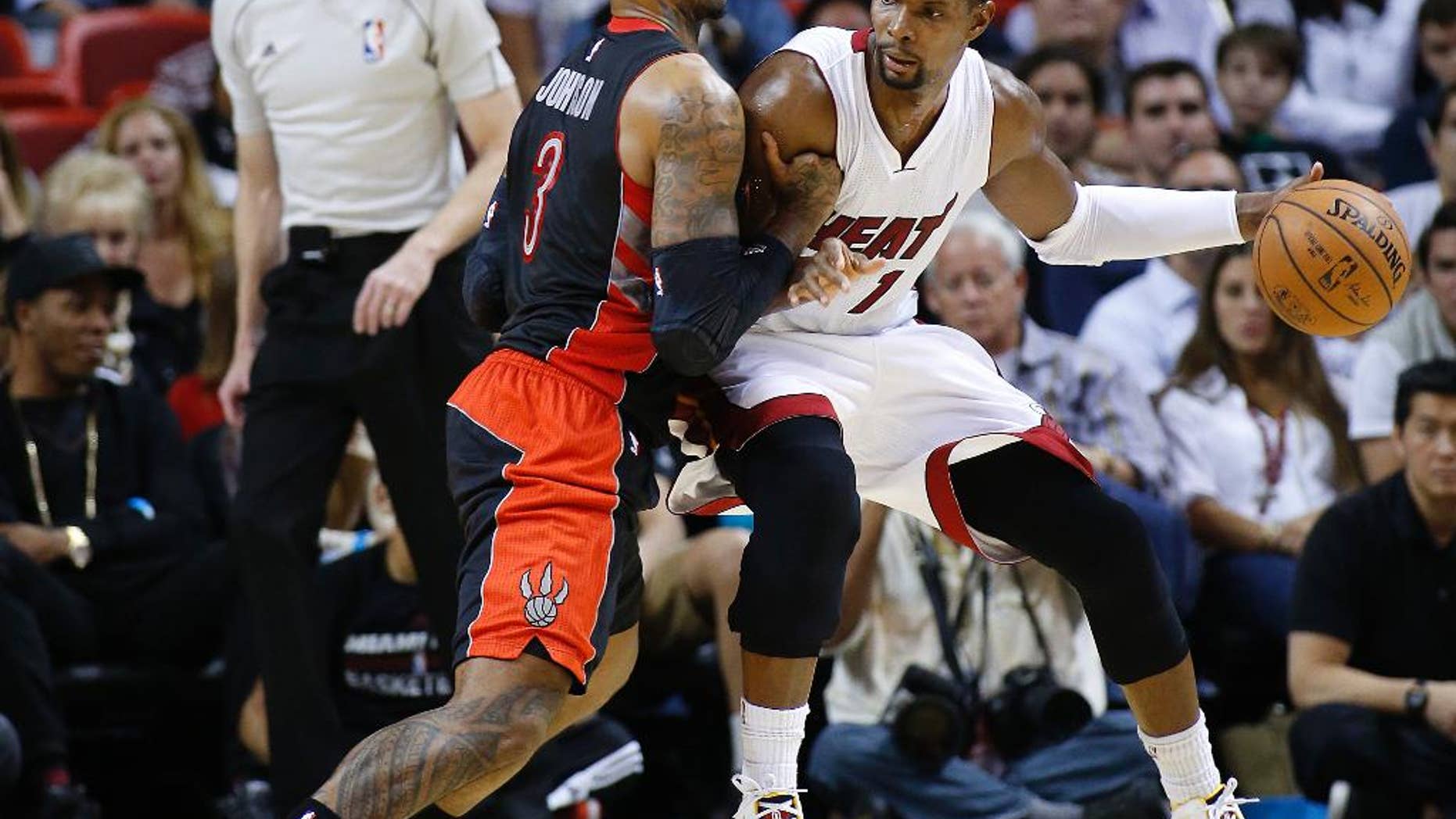 Toronto Raptors’ James Johnson (3) defends against Miami Heat's Chris Bosh (1) as he attempts to drive to the basket during the second half of an NBA basketball game in Miami, Sunday, Nov 2, 2014. The Heat defeated the Raptors 107-102. (AP Photo/Joel Auerbach)