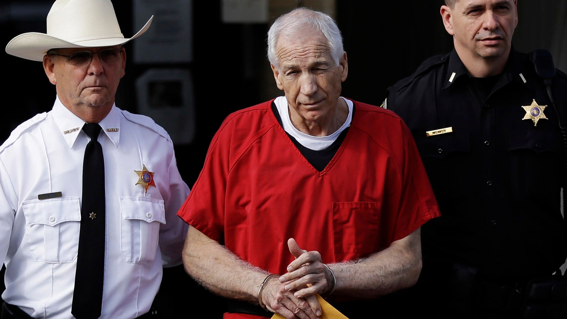 FILE - In this Oct. 9, 2012 file photo, former Penn State University assistant football coach Jerry Sandusky, center, is taken from the Centre County Courthouse after being sentenced in Bellefonte, Pa. Penn State on Monday Oct. 28, 2013 said it is paying $59.7 million to 26 young men over claims of child sexual abuse at the hands of former assistant football coach Jerry Sandusky, concluding negotiations that have lasted about a year. (AP Photo/Matt Rourke, File)