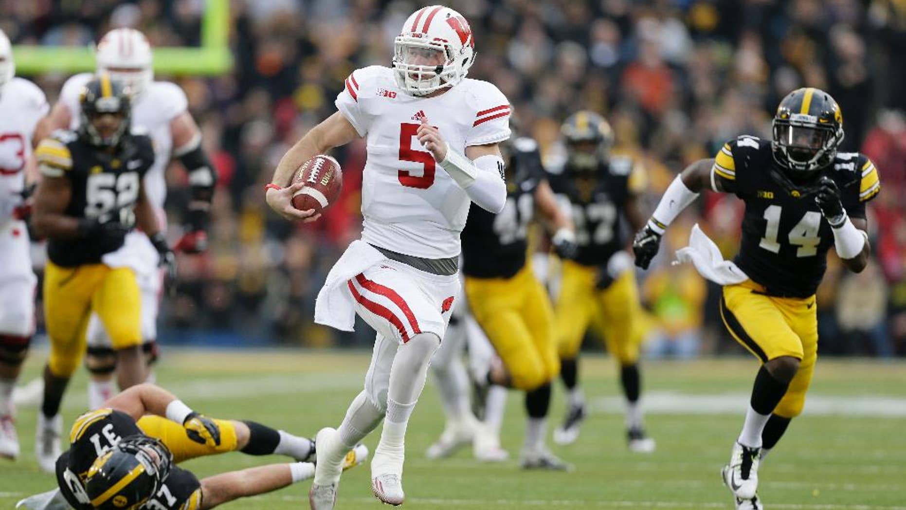 Wisconsin quarterback Tanner McEvoy (5) runs from Iowa defensive back John Lowdermilk (37) and defensive back Desmond King (14) during a 45-yard touchdown run in the first half of an NCAA college football game, Saturday, Nov. 22, 2014, in Iowa City, Iowa. (AP Photo/Charlie Neibergall)