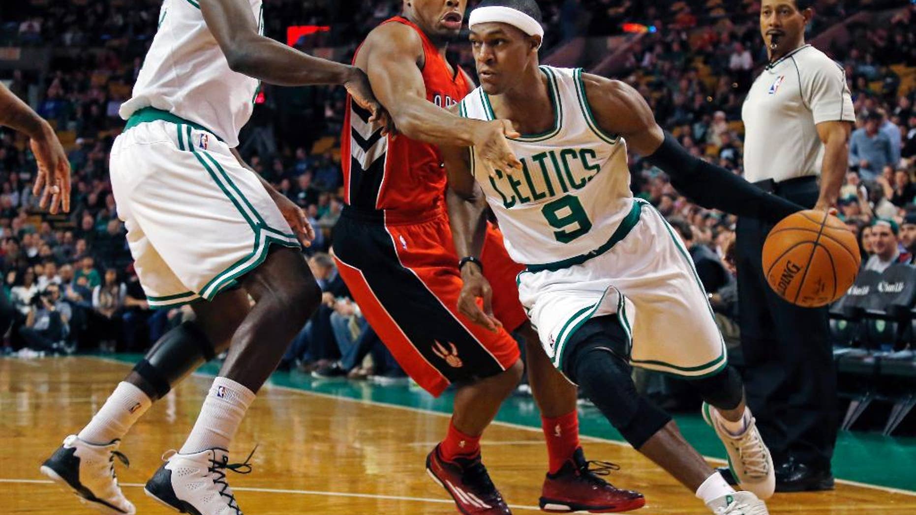 Boston Celtics guard Rajon Rondo (9) drives past Toronto Raptors guard Kyle Lowry, middle, during the first quarter of an NBA basketball game in Boston, Wednesday, Nov. 5, 2014. (AP Photo/Elise Amendola)