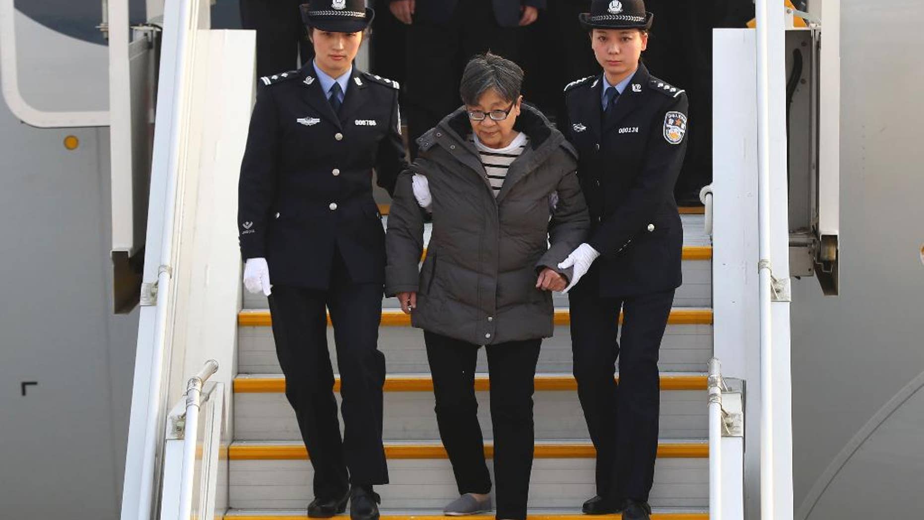 Yang Xiuzhu is escorted down a plane upon arriving at the Beijing Capital International Airport.