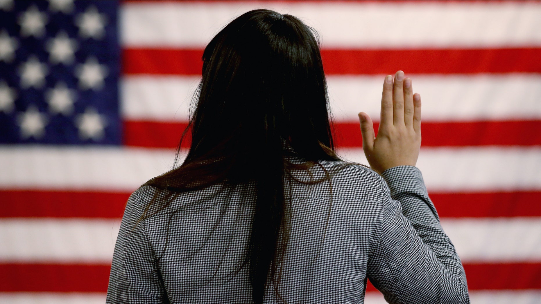 NEWARK, NJ - JANUARY 28: An woman takes the oath of allegiance during a naturalization ceremony at the at district office of the U.S. Citizenship and Immigration Services (USCIS) on January 28, 2013 in Newark, New Jersey. Some 38,000 immigrants became U.S. citizens at the Newark office alone in 2012. (Photo by John Moore/Getty Images)