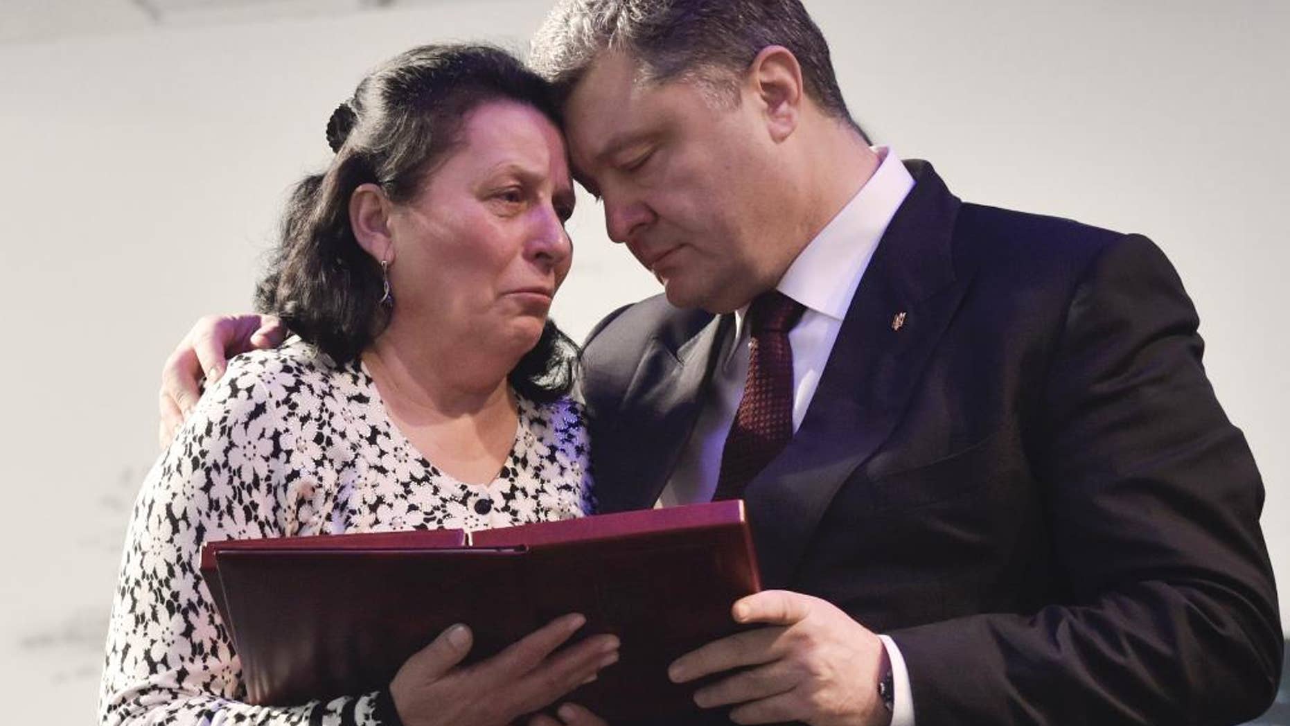 Ukrainian President Petro Poroshenko, right, presents a Hero of Ukraine award to a relative of an activist killed a year ago during mass protests, at the award ceremony in Kiev, Ukraine, Friday, Feb. 20, 2015. (AP Photo/Mykola Lazarenko, Pool)