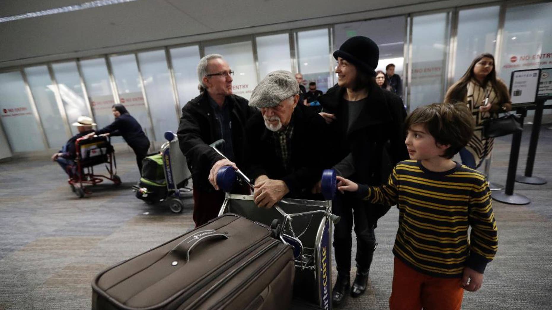FILE - In this Saturday, Jan. 28, 2017, file photo, Abdollah Mostafavi, center, arriving from Tehran, Iran, is met by his family including son-in-law Nasser Sorkhavi, left, daughter Mozhgan Mostafavi, second from right, and grandson Kourosh Sorkhavi at San Francisco International Airport in San Francisco. Mostafavi was held at the airport for some time as a result of President Donald Trump's executive order. A federal judge has granted a preliminary injunction barring the Trump administration from implementing its travel ban in Virginia. A federal appeals court in California has already upheld a national temporary restraining order stopping the government from implementing the ban. (AP Photo/Marcio Jose Sanchez, File)