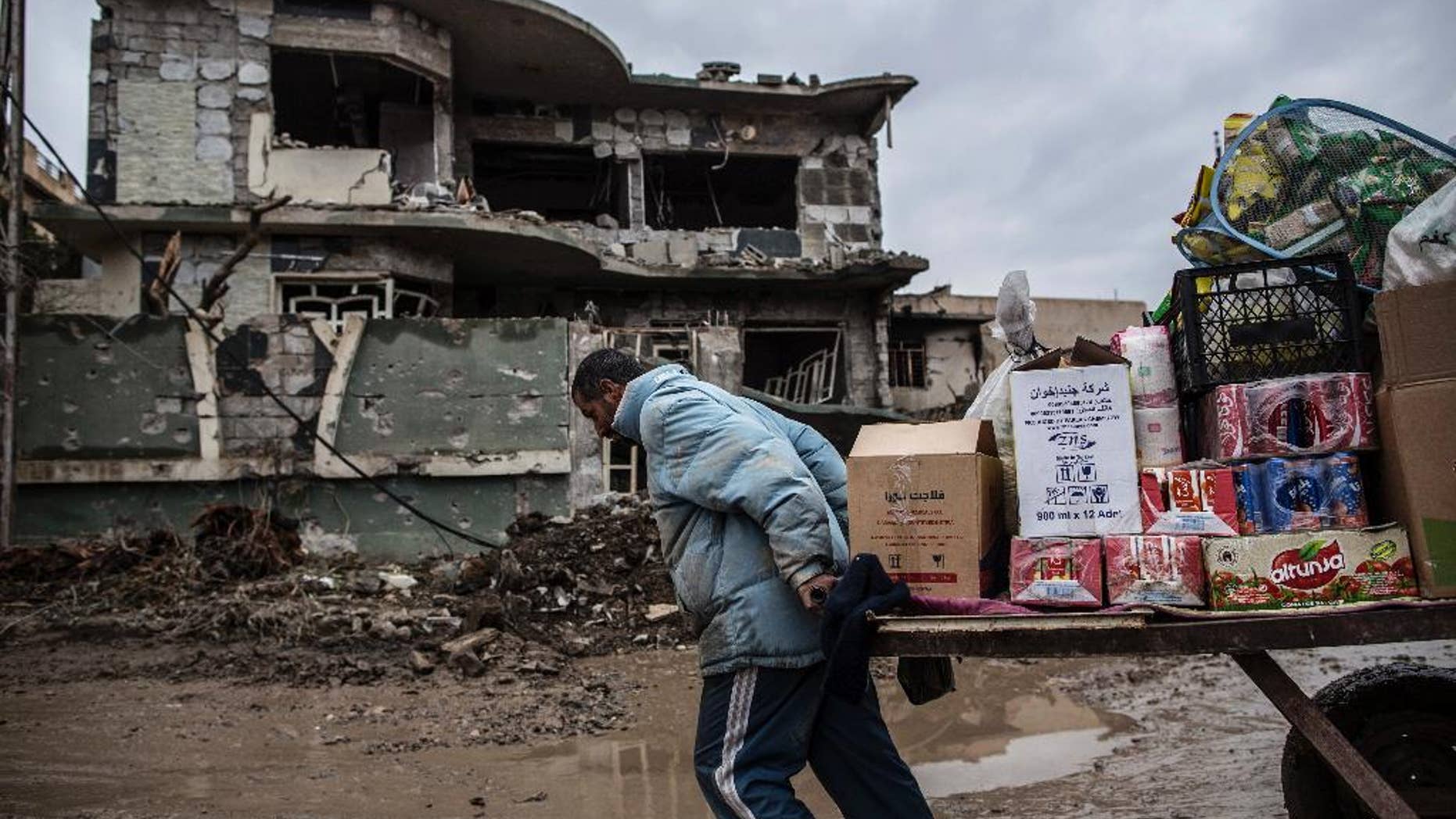 A street vendor pulls his cart in front of a house damaged by the fight in Mishraq district in Mosul, Iraq, Tuesday, Dec. 20, 2016. Advancing into Mosul has become a painful slog for Iraqi forces. Islamic State group militants have fortified each neighborhood, unlike past battles where they concentrated their defenses in one part of the city. (AP Photo/Manu Brabo)