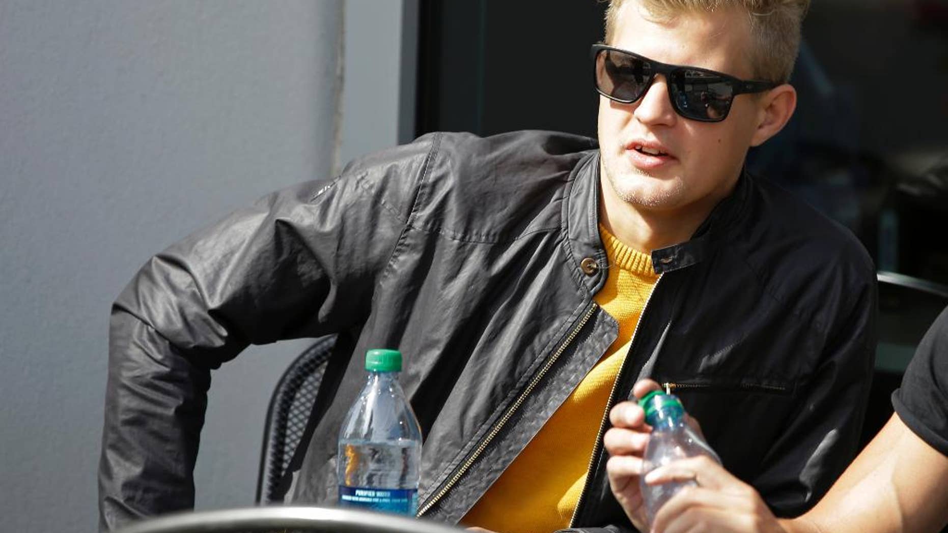 Caterham driver Marcus Ericsson, of Sweden, sits outside of the media center before the start of the Formula One U.S. Grand Prix auto race at the Circuit of the Americas, Sunday, Nov. 2, 2014, in Austin, Texas. The Formula One teams of Caterham and Marussia teams in administration and are absent from the race. (AP Photo/Darron Cummings)