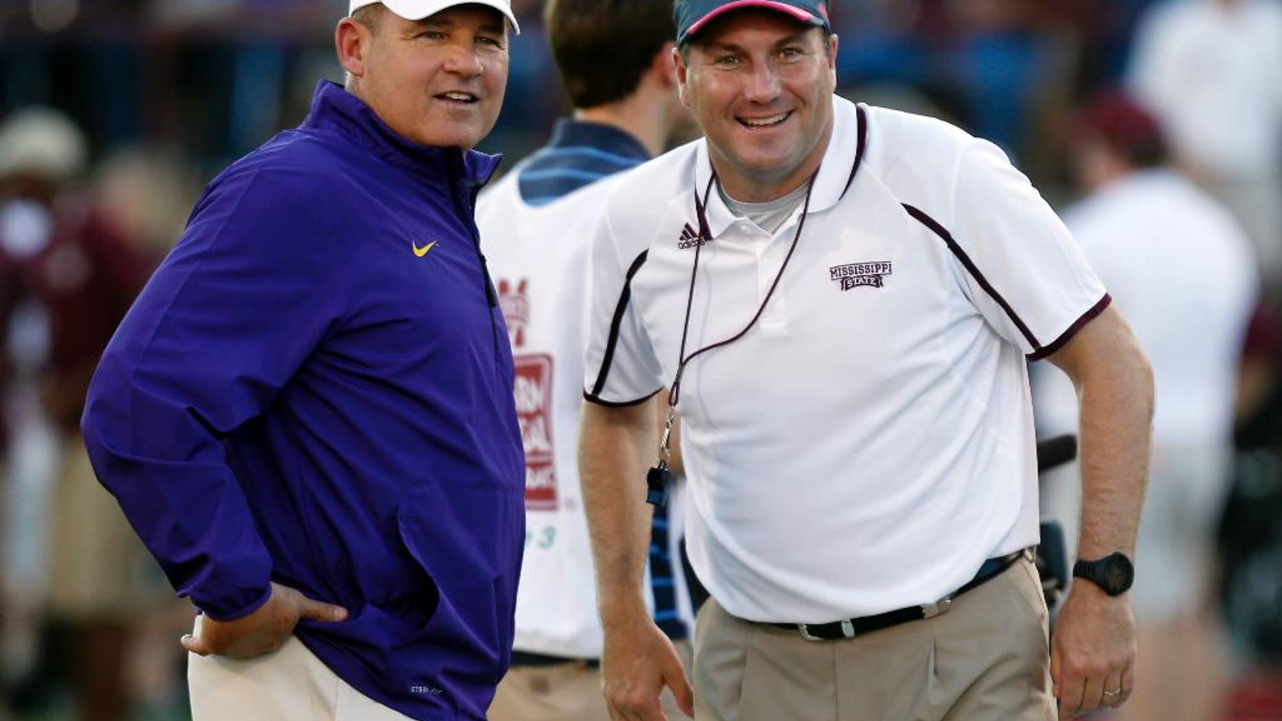 FILE - In this Oct. 5, 2013, file photo, LSU coach Les Miles, left, and Mississippi State coach Dan Mullen smile prior to an NCAA college football game in Starkville, Miss. The Bulldogs feel like they have the talent to end their 14 game losing streak against LSU on Saturday, but it won't be easy at Tiger Stadium.(AP Photo/Rogelio V. Solis, File)