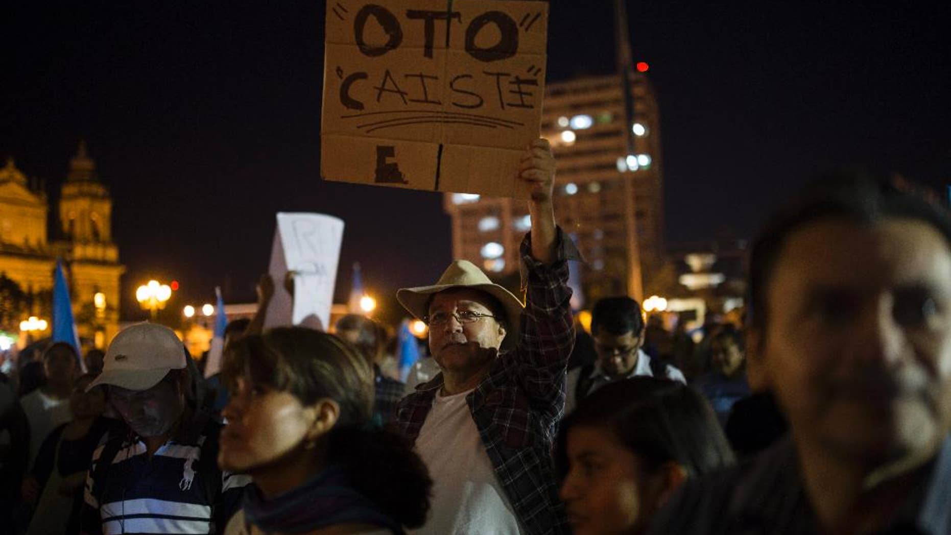 A protester holds a sign that reads in Spanish "Otto, you're down," referring to President Otto Perez Molina, after the arrest of his former Vice President Roxana Baldetti, who was arrested in connection with a corruption scandal, in the Central Park of Guatemala City, Friday, Aug. 21, 2015. Baldetti was detained Friday in connection with a customs corruption scandal that led to her resignation, and prosecutors announced they are also seeking to investigate the president in the matter. (AP Photo/Luis Soto)