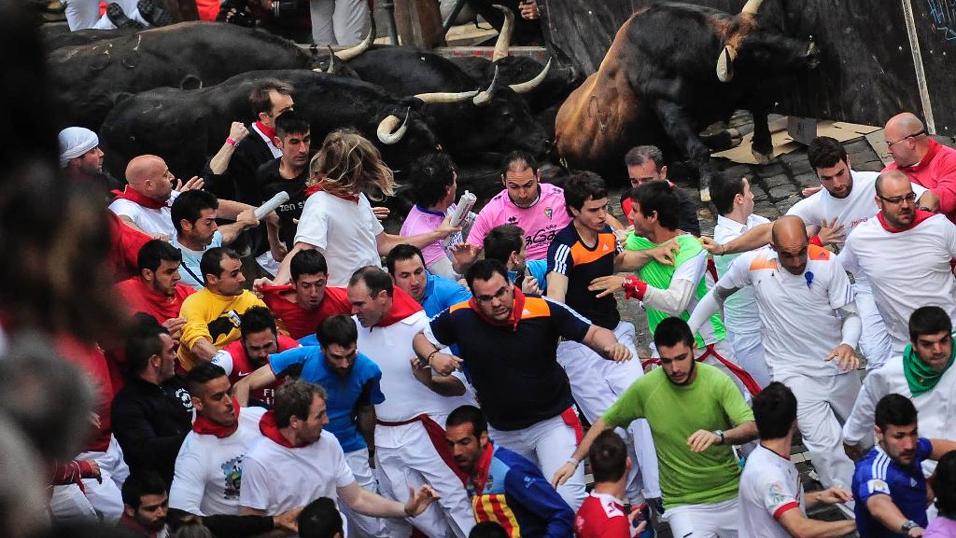 Revelers run ahead of ''Jandilla'' fighting bulls on Estafeta corner on the way to the bull ring, during the running of the bulls, at the San Fermin festival, in Pamplona, Spain, Friday, July 11, 2014. Revelers from around the world arrive to Pamplona every year to take part in some of the eight days of the running of the bulls. (AP Photo/Alvaro Barrientos)