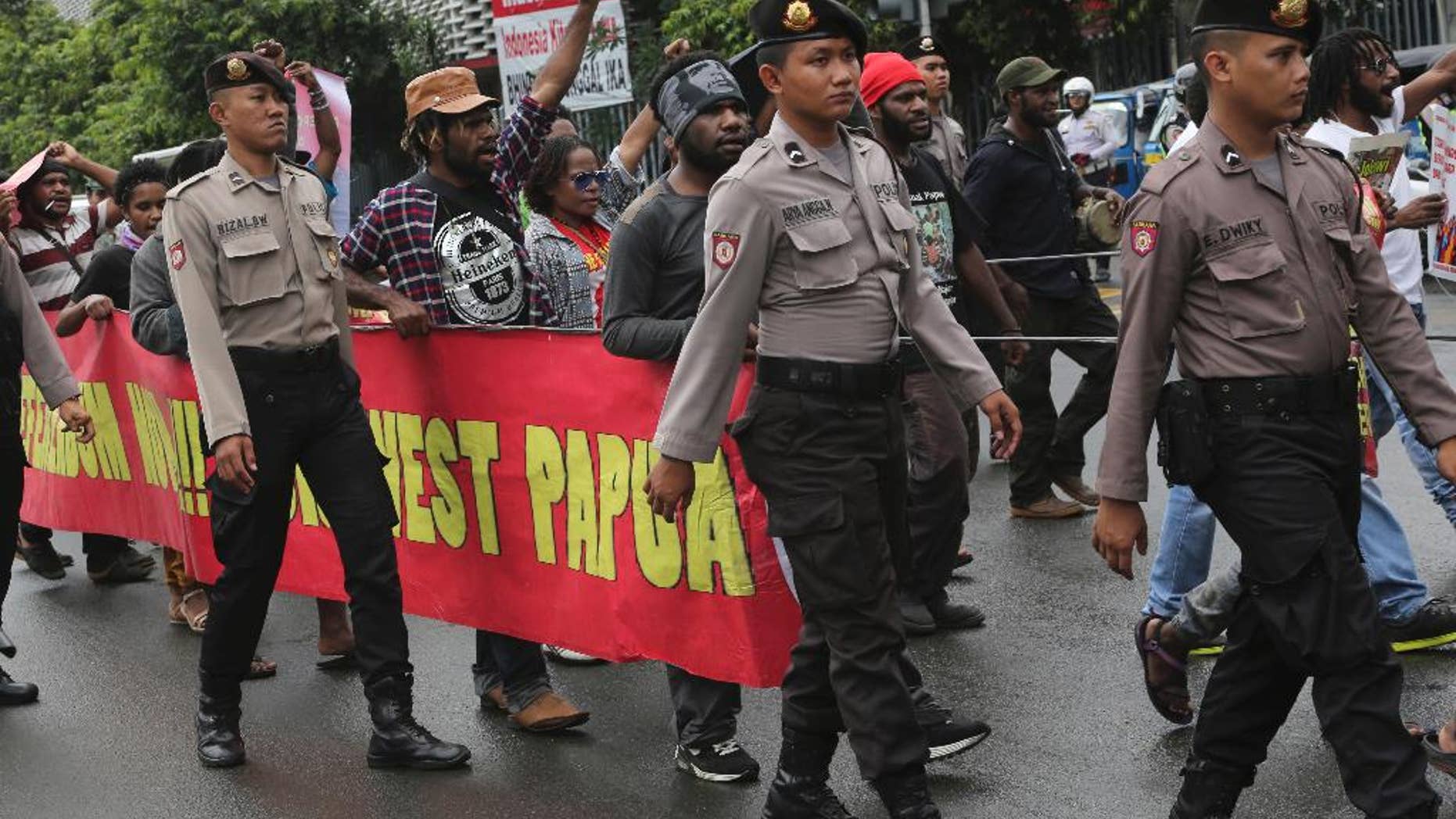 Police officers escort Papuan protesters during a rally marking the 55th anniversary of the official declaration of an Indonesian military campaign to take control of West Papua from the Dutch, in Jakarta, Indonesia, Monday, Dec. 19, 2016. Indonesian police detained several hundred people Monday at protests in cities in Sulawesi, Java and Papua demanding independence for remote West Papua. Police in the capital Jakarta had warned organizers against protesting but relented and allowed the group of about 50 people to march down a main thoroughfare. (AP Photo/Tatan Syuflana)