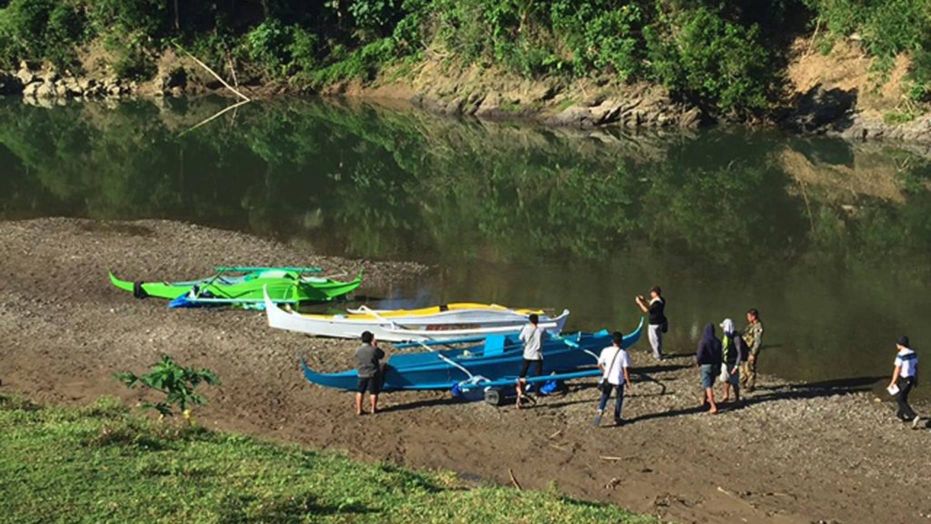 FILE - This undated photo provided by the Armed Forces of the Philippines on April 12, 2017, shows people stand by boats which the military said were used by Abu Sayyaf militants to enter the Ibananga River in Bohol province, central Philippines, as government troopers continue clearing operations. Philippine officials said Saturday, April 15, 2017, that an investigation shows that a foiled attack on a resort island this week was a kidnapping and bombing mission by at least three nascent groups affiliated with the Islamic State group. (3rd ID, Armed Forces of the Philippines via AP, File)