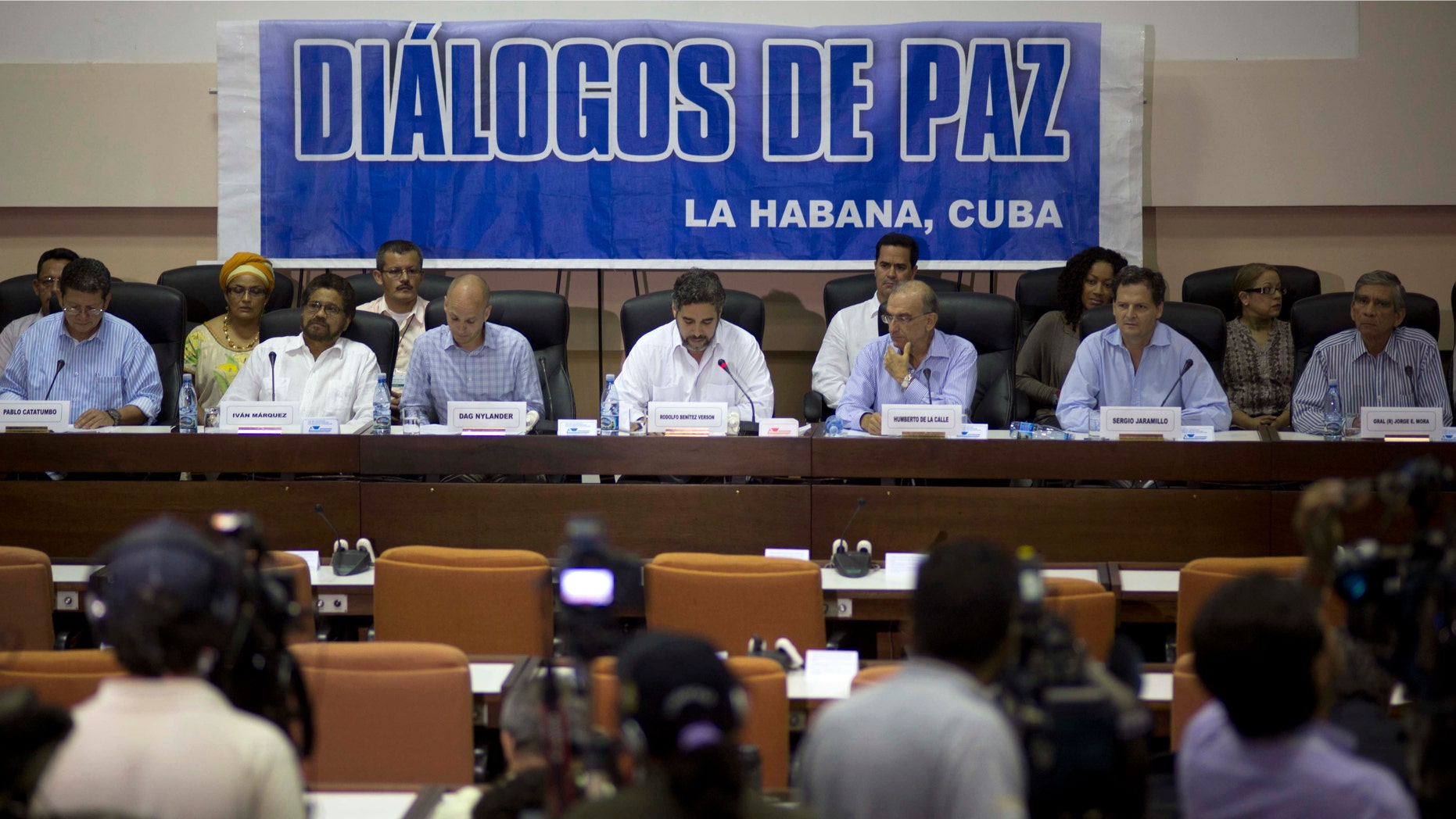 FILE - In this May 16, 2014 file photo, negotiators from the Revolutionary Armed Forces of Colombia (FARC), left, and Colombia's government, right, give a press conference under a sign that reads in Spanish "Peace Talks" in Havana, Cuba. Colombia's government has rebuffed a unilateral truce declared on Wednesday, Dec. 18, 2014 by the country's largest rebel group, saying conditions demanded by the guerrillasâ are unacceptable until a peace deal is reached. Sitting at the table, from left, are chief of the western bloc of the FARC Pablo Catatumbo, FARC chief negotiator Ivan Marquez, Norwegian guarantor Dag Nylander, Cuban guarantor Rodolfo Benitez Verson, head of Colombia's government team Humberto de la Calle, government negotiator Sergio Jaramillo, and government negotiator Gen. Jorge Mora. (AP Photo/Ramon Espinosa, File)