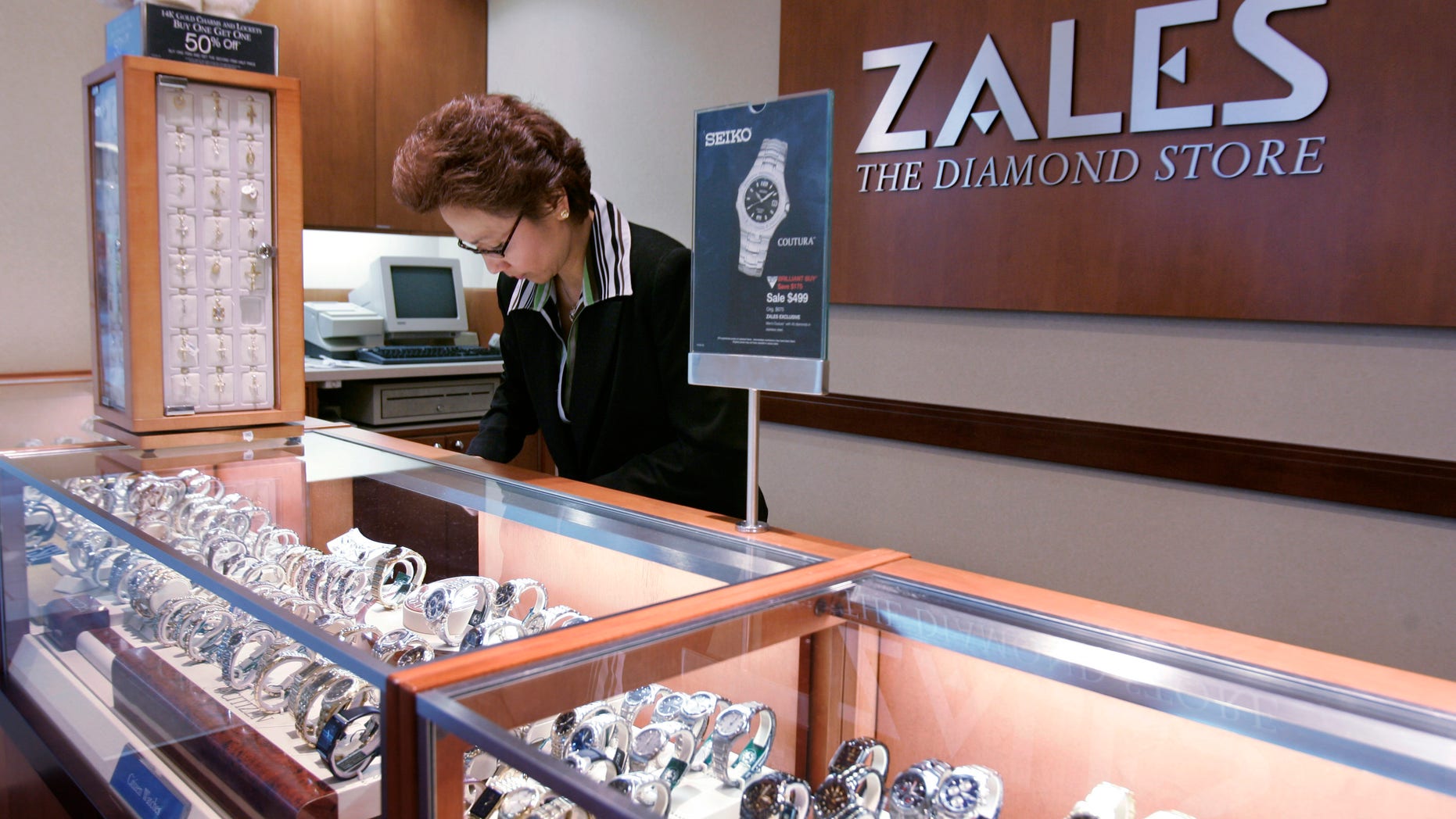 FILE - In this Jan. 4, 2007, a Zales jewelry store worker looks at watches in San Bruno, Calif. Signet Jewelers is buying Zale Corp. for approximately $690 million to help diversify its business and expand further internationally. Shares of Zale soared more than 39 percent in Wednesday, Feb. 19, 2014, premarket trading, while Signet Jewelers Ltd.' stock rose more than 9 percent. (AP Photo/Paul Sakuma, file)