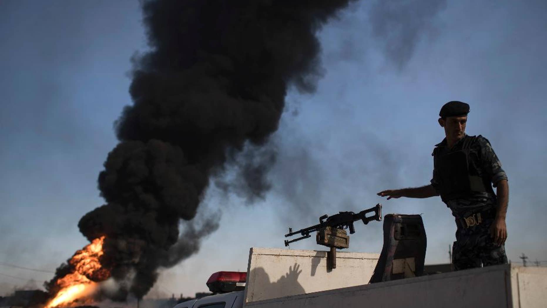 An Iraqi army soldier stands at the back of a pickup truck next to a burning oil field in Qayara, south of Mosul, Iraq, Thursday, Nov. 3, 2016. A senior military commander says more than 5,000 civilians have been evacuated from newly-retaken eastern parts of the Islamic State group-held city of Mosul and taken to camps. (AP Photo/Felipe Dana)