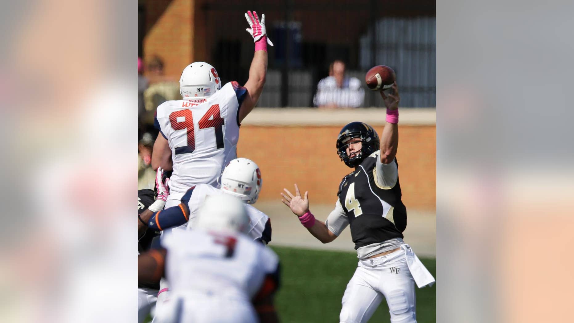 Wake Forest's Tyler Cameron (4) tries to throw a pass over Syracuse's Robert Welsh (94) during the second half of an NCAA college football game in Winston-Salem, N.C., Saturday, Oct. 18, 2014. Syracuse won 30-7. (AP Photo/Chuck Burton)