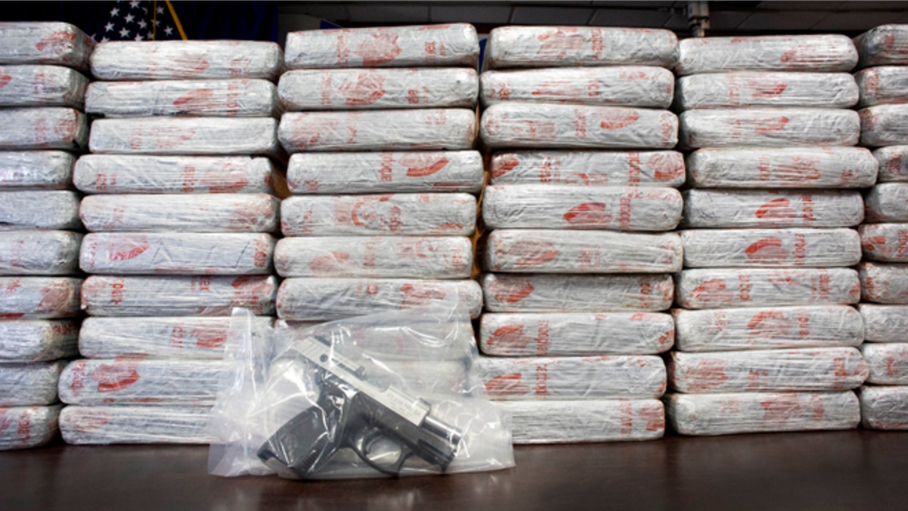 A firearm and 154 pounds of heroin worth at least $50 million are displayed by DEA, Tuesday, May 19, 2015 in New York.