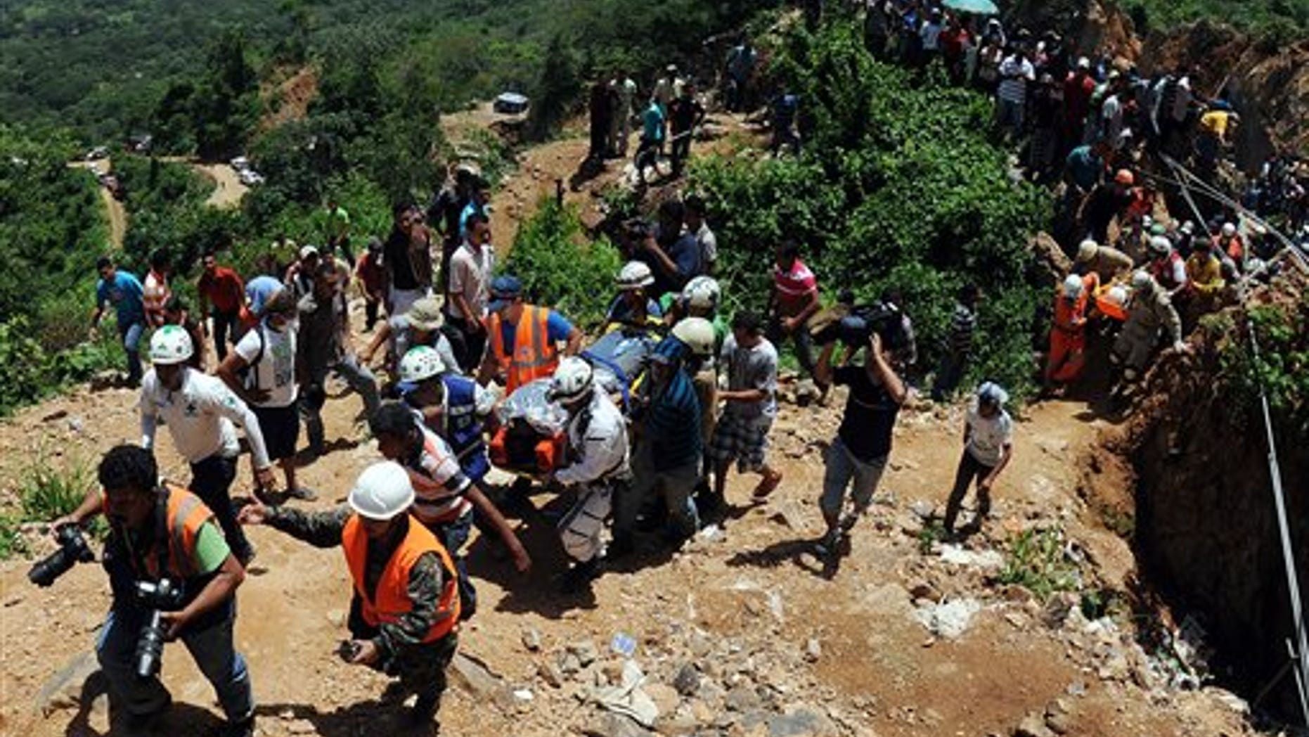 Rescue workers carry a miner who was trapped in a gold mine after a landslide in San Juan Arriba, Choluteca in southern Honduras, Friday July 4, 2014. Three miners were rescued Friday after spending more than two days trapped following a collapse at a small, wildcat gold mine. Eight others remain missing. (AP Photo/Fernando Antonio)