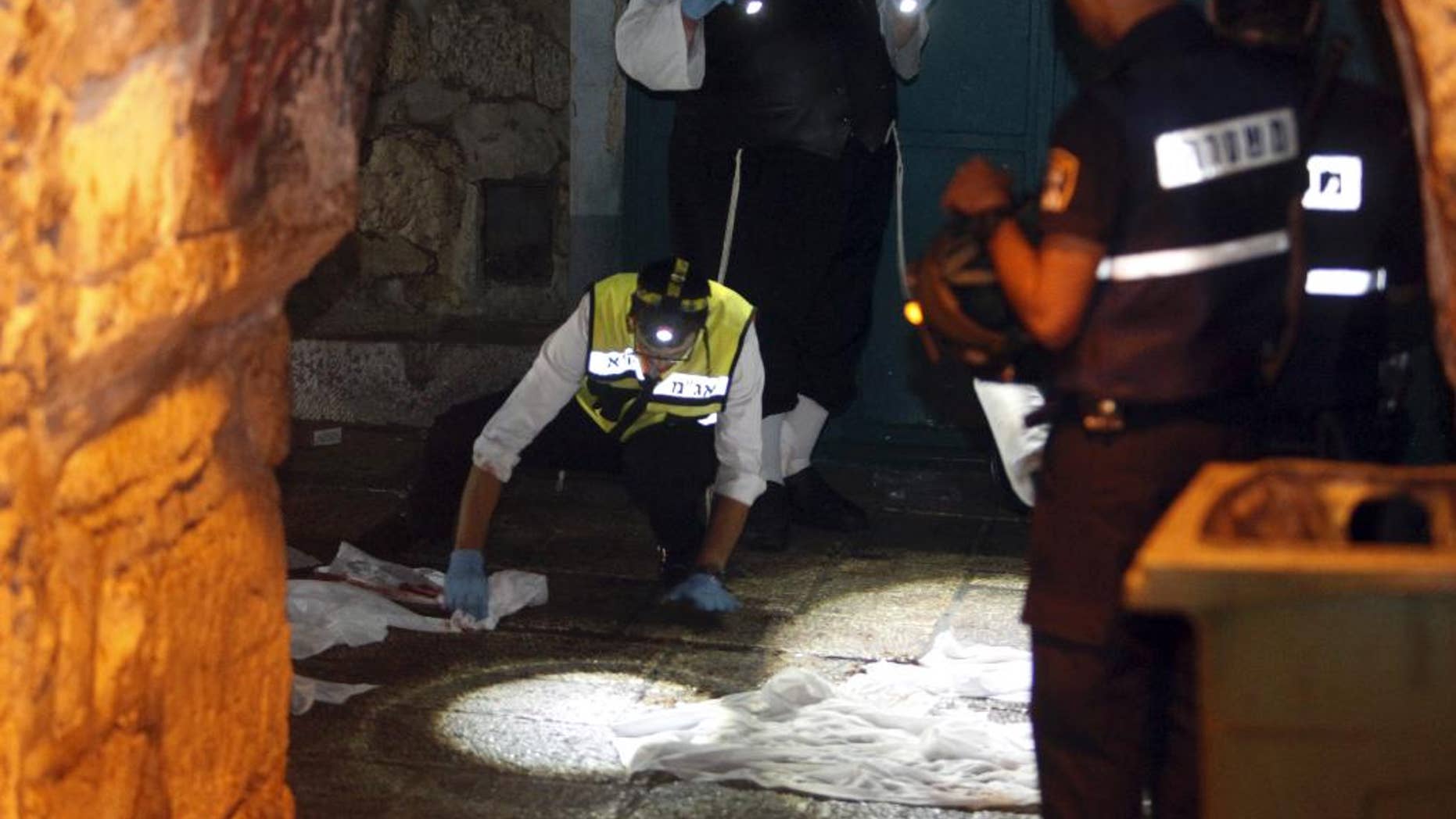 Israeli forensic inspect the scene of an attack in Jerusalem's Old City, Saturday, Oct. 3, 2015. A Palestinian fatally stabbed two Israelis as they walked in Jerusalem's Old City and seriously injured a toddler and a woman, before he was shot and killed by an officer on duty, police said Saturday in the latest in a series of Palestinian attacks. (AP Photo/Mahmoud Illean)