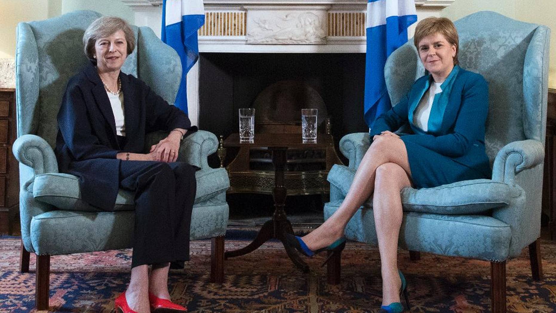 Britain's new Prime Minister Theresa May, left, meets with First Minister of Scotland, Nicola Sturgeon at Bute House in Edinburgh, Scotland, Friday July 15, 2016, with Scottish saltire flags behind. Prior to the meeting, May said "This visit to Scotland is my first as prime minister and I'm coming here to show my commitment to preserving this special union that has endured for centuries." (Pool via AP)
