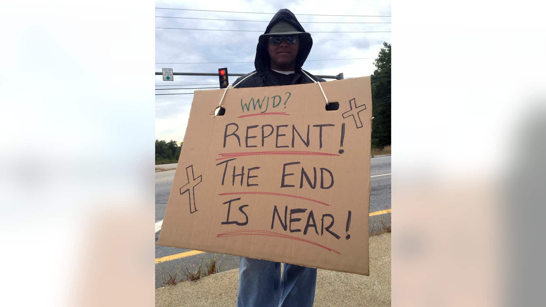 Sept. 21, 2015: Officer Anthony McKnight poses undercover in Somersworth, N.H., with a sign, intending to catch violators of the state’s ban on the use of hand-held phones or electronic devices while driving.