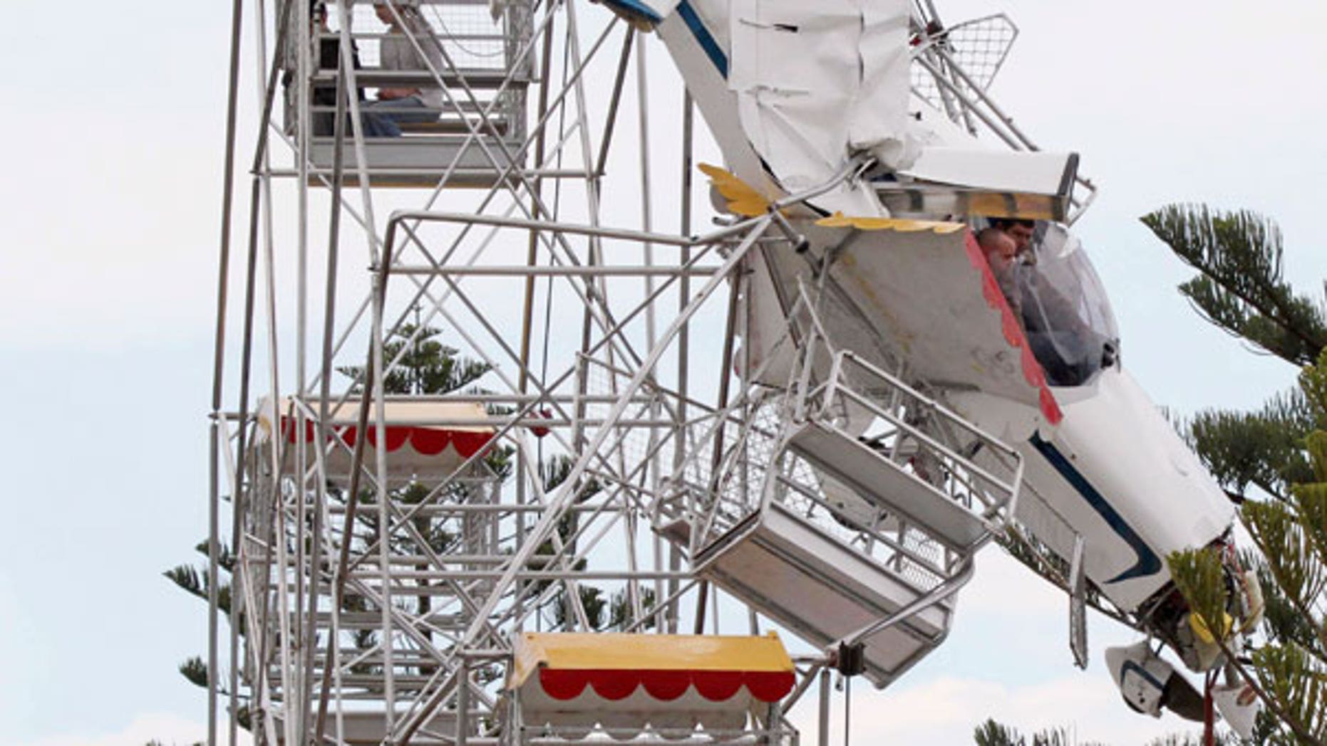 Oct. 1: Two men and their ultra-light plane hang from a Ferris wheel while two children sit in a carriage near the top of the ride at a country festival at Old Bar, Australia.