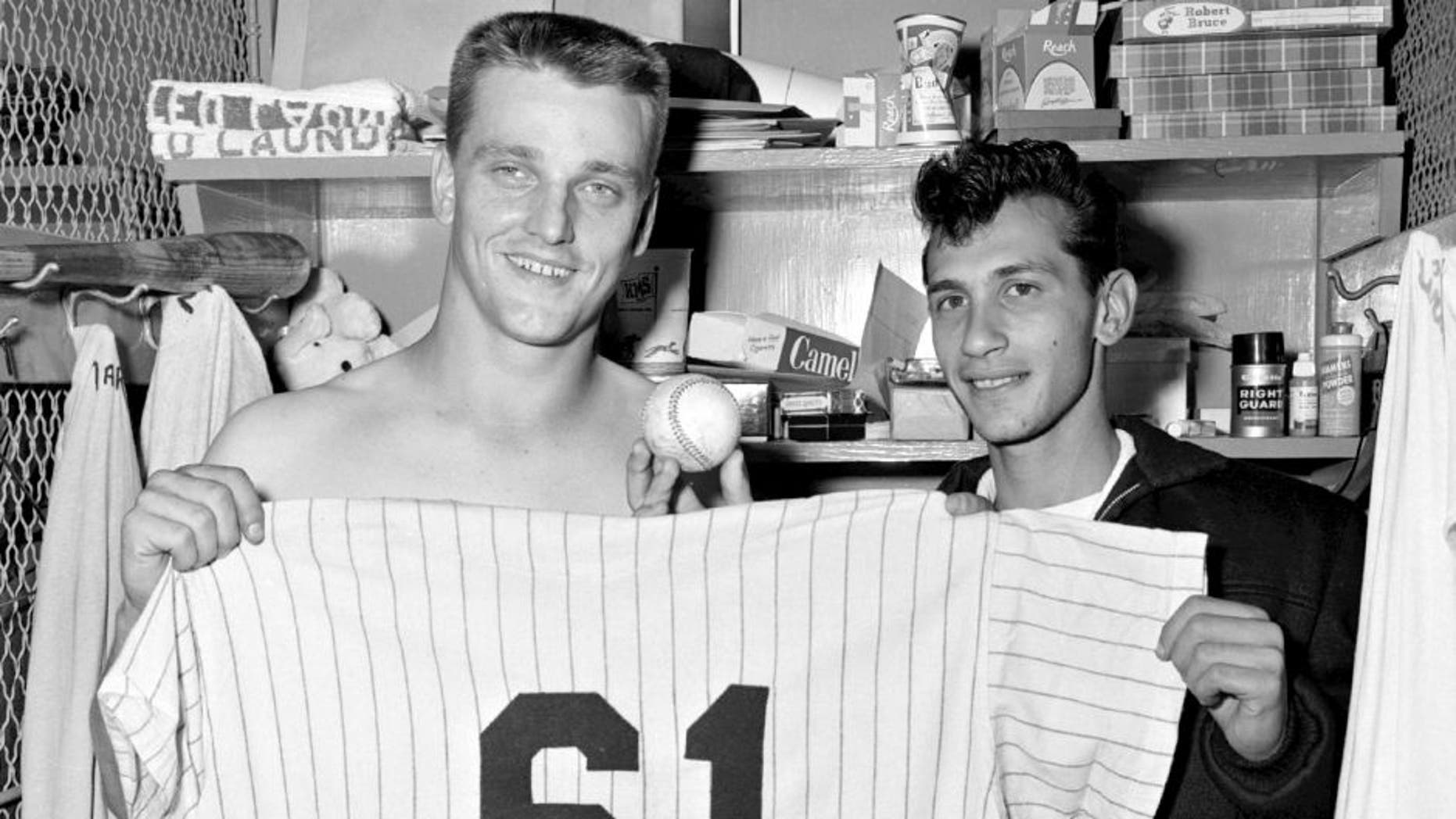 BRONX, NY - OCTOBER 1, 1961: Outfielder Roger Maris, of the New York Yankees, holds up uniform number 61 after he hit his 61st home run of the season off Tracy Stallard, of the Boston Red Sox, as the Yankees won, 2-0 on October 1, 1961 at Yankee Stadium in New York. Maris' 61 homers eclipses the record established by Babe Ruth for the Yankees in 1927. Joining Maris in his locker is Sal Durante, the fan who caught the ball in the rightfield stands. (Olen Collection/Diamond Images/Getty Images)
